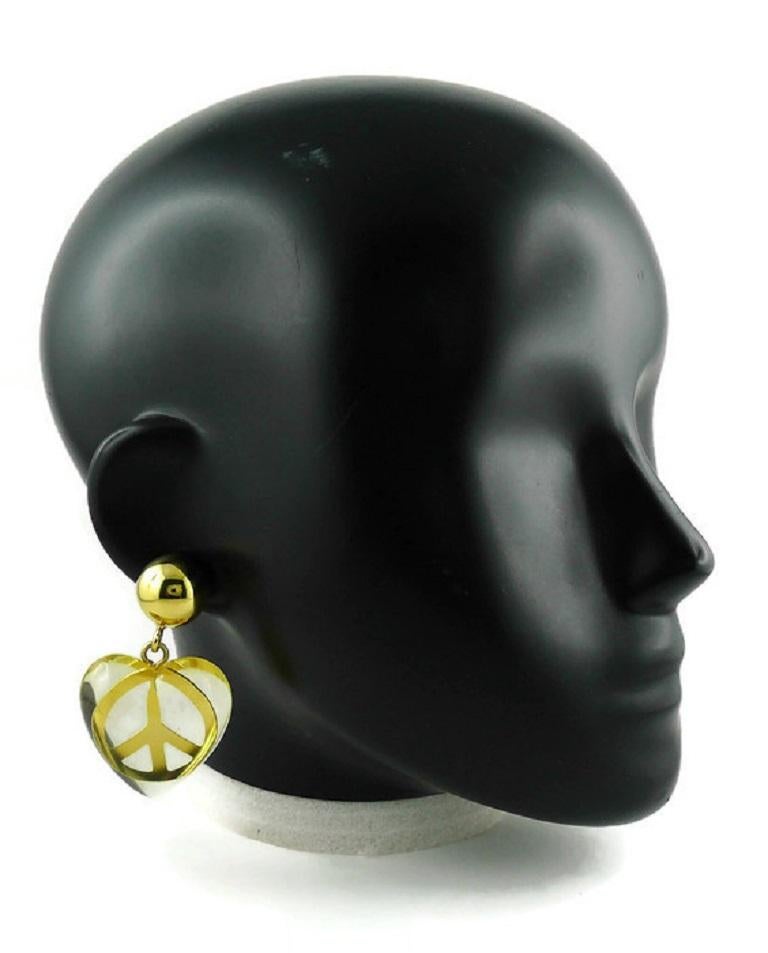 MOSCHINO vintage gold toned dangling earrings (clip-on) featuring a resin heart with a peace sign insert.

Embossed MOSCHINO.

Indicative measurements : height approx. 6.5 cm (2.56 inches) / max. width approx. 3.8 cm (1.50 inches).

JEWELRY
