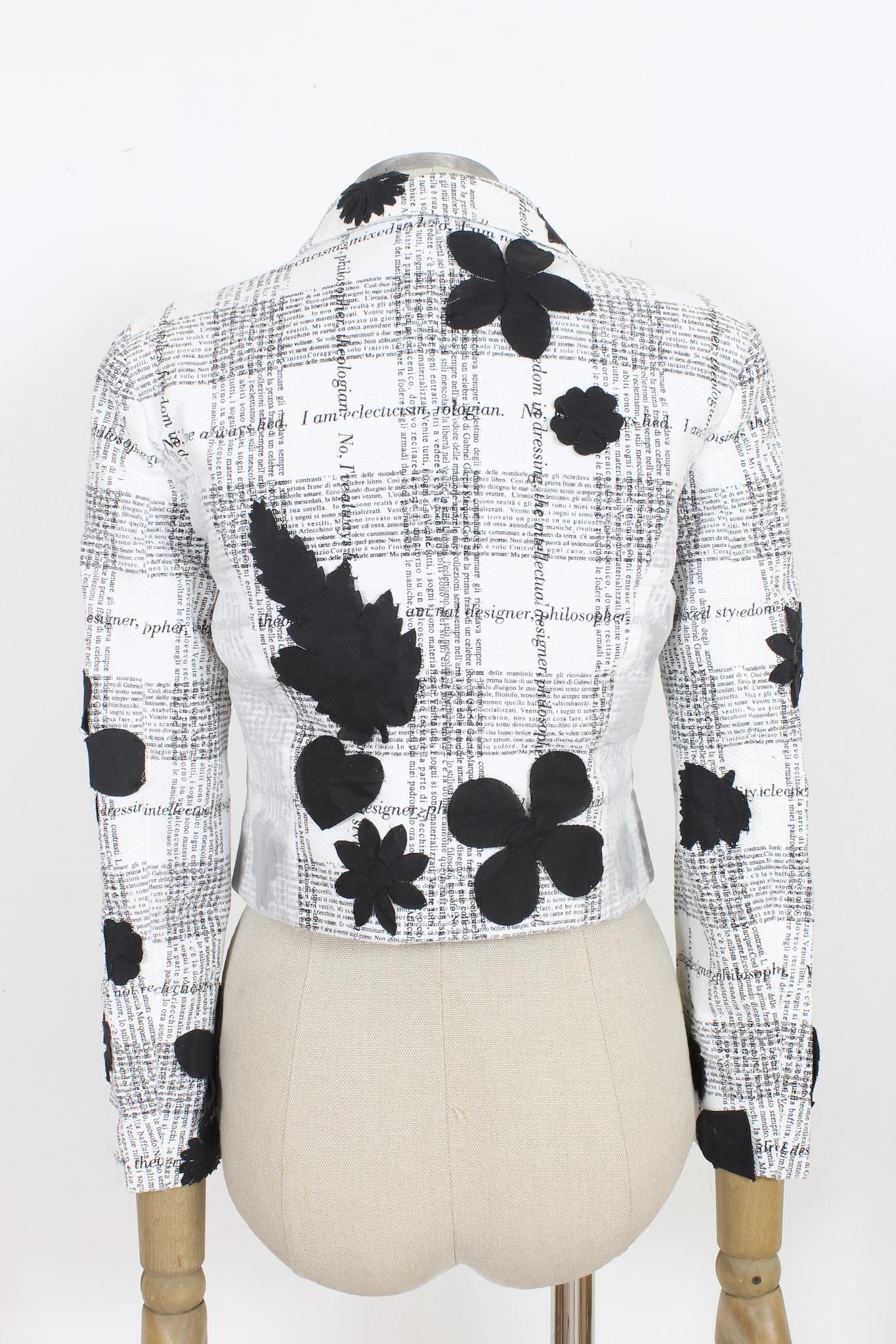 This Moschino Cheap and Chic white and black cotton vintage short floral jacket is a classic 90s style piece. Embroidered with black floral patterns, printed text, some places are covered with a semi-transparent veil. Crafted from quality cotton, it