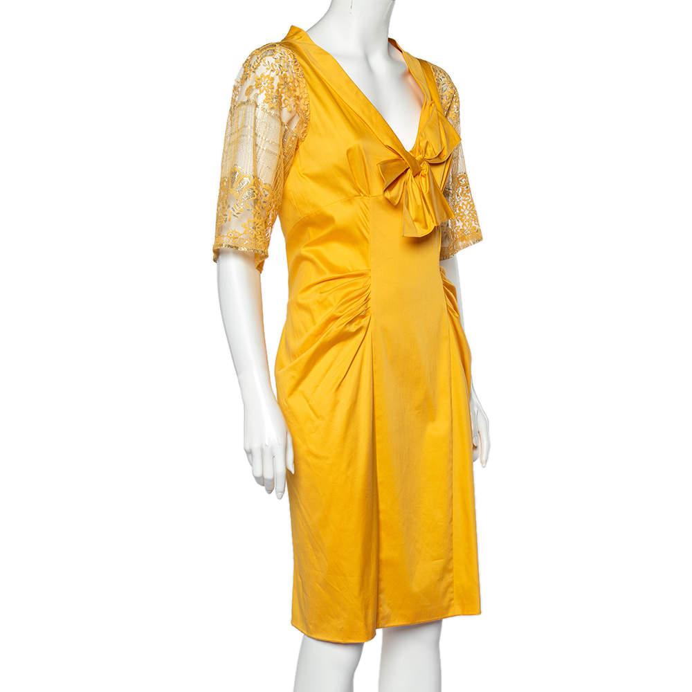 Masterful tailoring and pure designing characterize this midi dress from the House of Moschino. It is draped beautifully using yellow cotton with lace sleeves, a bow detail on the front, and a stunning, steep neckline. This gorgeous dress offers a