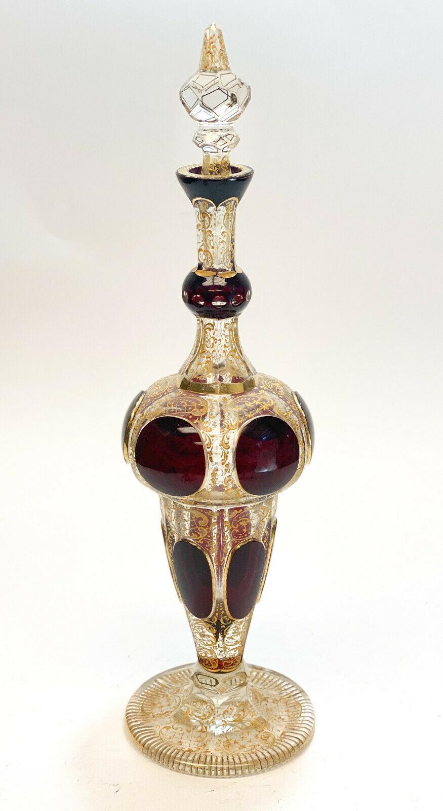 Moser cabochon & raised gilt garnet red to clear glass liquor set for 5, circa 1900. Gilt foliate scroll and beaded designs throughout with garnet red cabochon panels throughout the pieces. The liquor set includes a decanter and 5 cordial wine