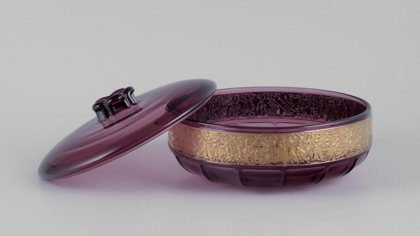 Moser, Czech Republic. Large covered bowl in art glass. 
Purple glass with gold motifs.
Mid-20th century.
In perfect condition.
Dimensions: Diameter 20.0 cm x Height 11.0 cm.