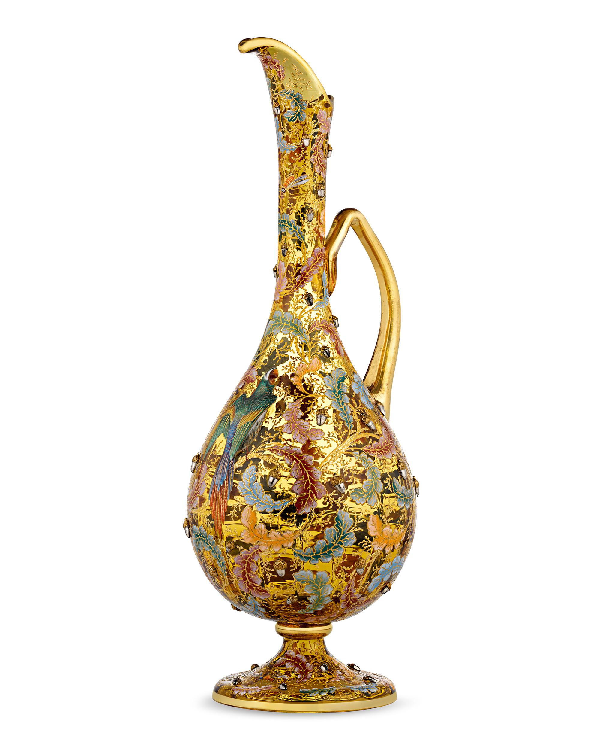 Vibrantly colored enamel decoration and gilt detailing distinguishes this exquisite amber glass ewer by Moser. Applied enamel acorns are surrounded by colorful oak leaves in this highly desirable and charming motif, which perfectly captures the
