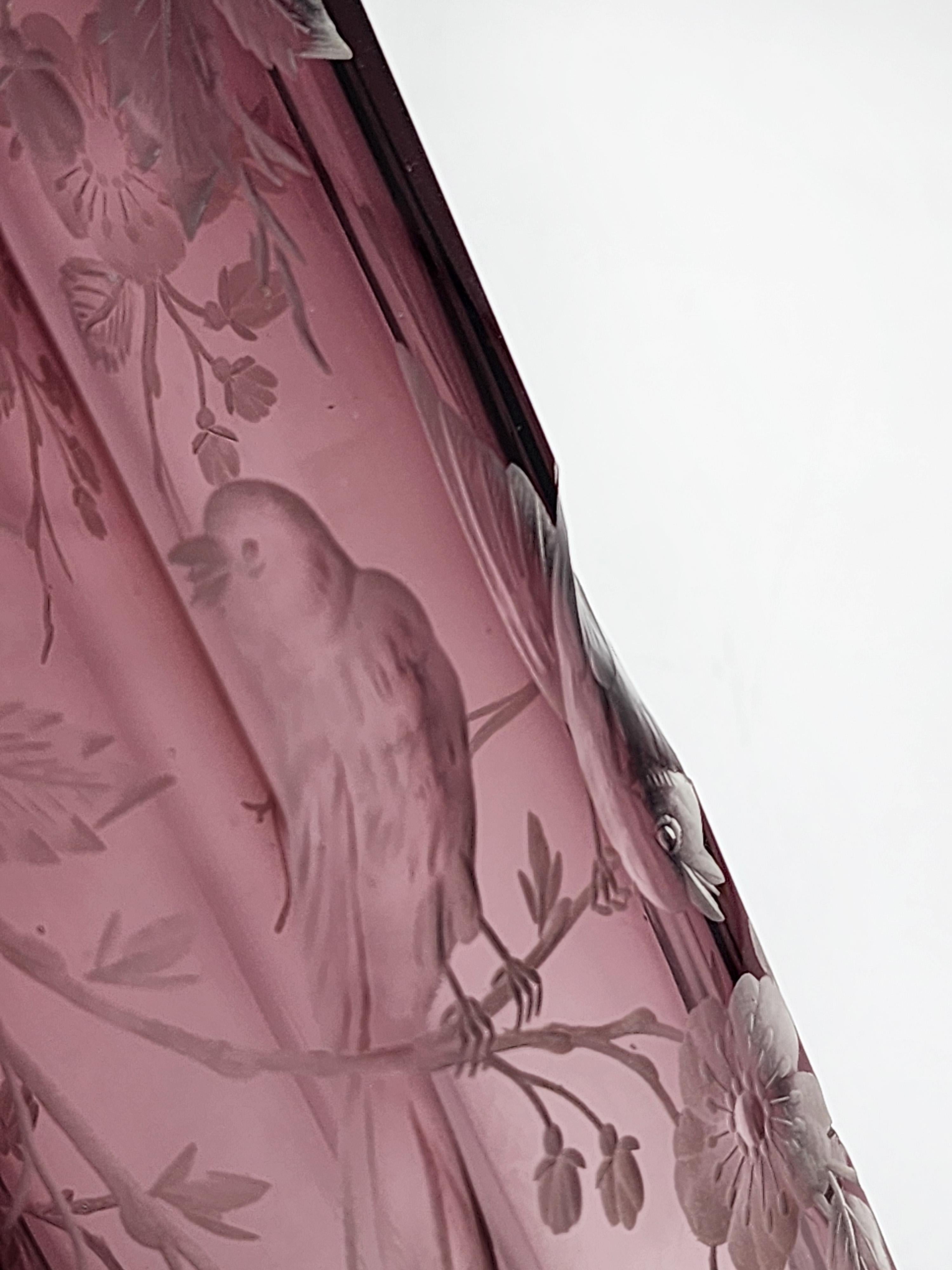Moser Karlsbad Cut Glass Vase
This Moser Karlsbad glass vase features a hexagonal design with intricate engraving detailing flowering branches and perched birds, all carved on an amethyst-hued glass background. The piece has a faceted design on both
