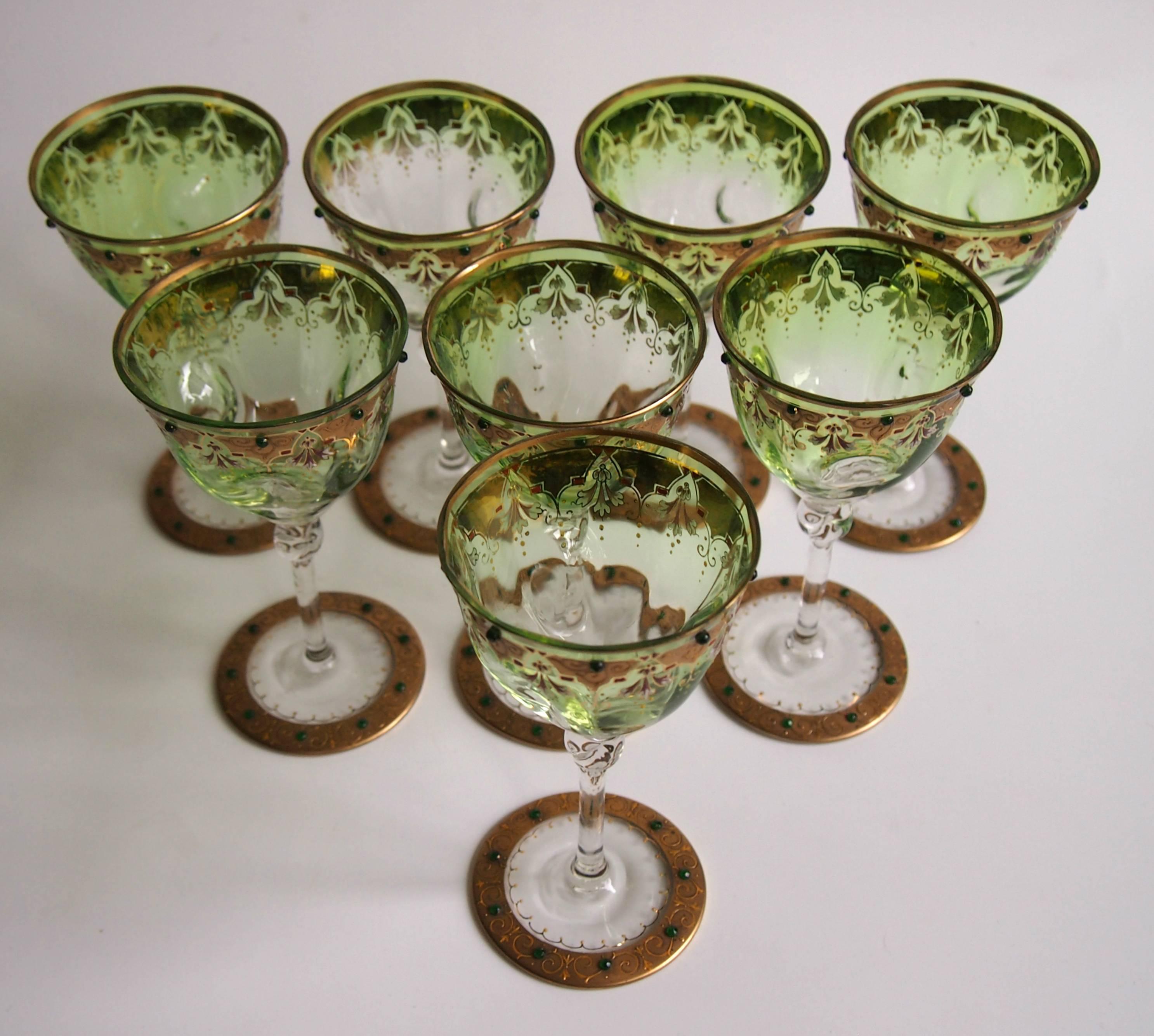 Rare set of eight Moser, early Art Nouveau, green graduating to clear jewelled, gilded and enamelled wine glasses. The glasses have a twisted knop just below the bowl and three dimples in each bowl. We've not seen the glass shapes before, but the