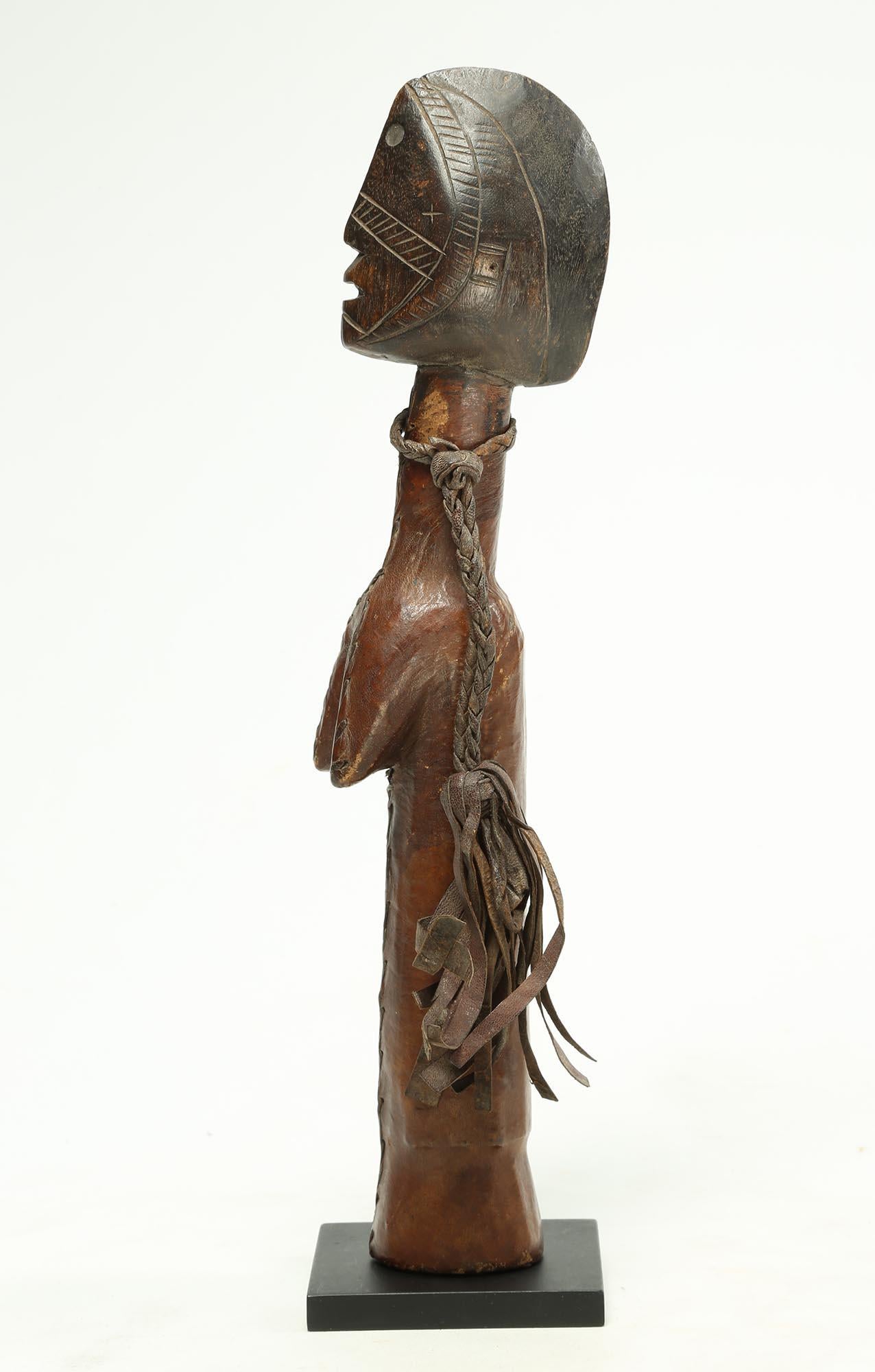 Striking carved wood Mossi doll figure (biga) with rare leather covering. The head slightly tilted upward as though star gazing, giving this one great personality and animation. Classic Mossi scarification marks around face, early 20th century.