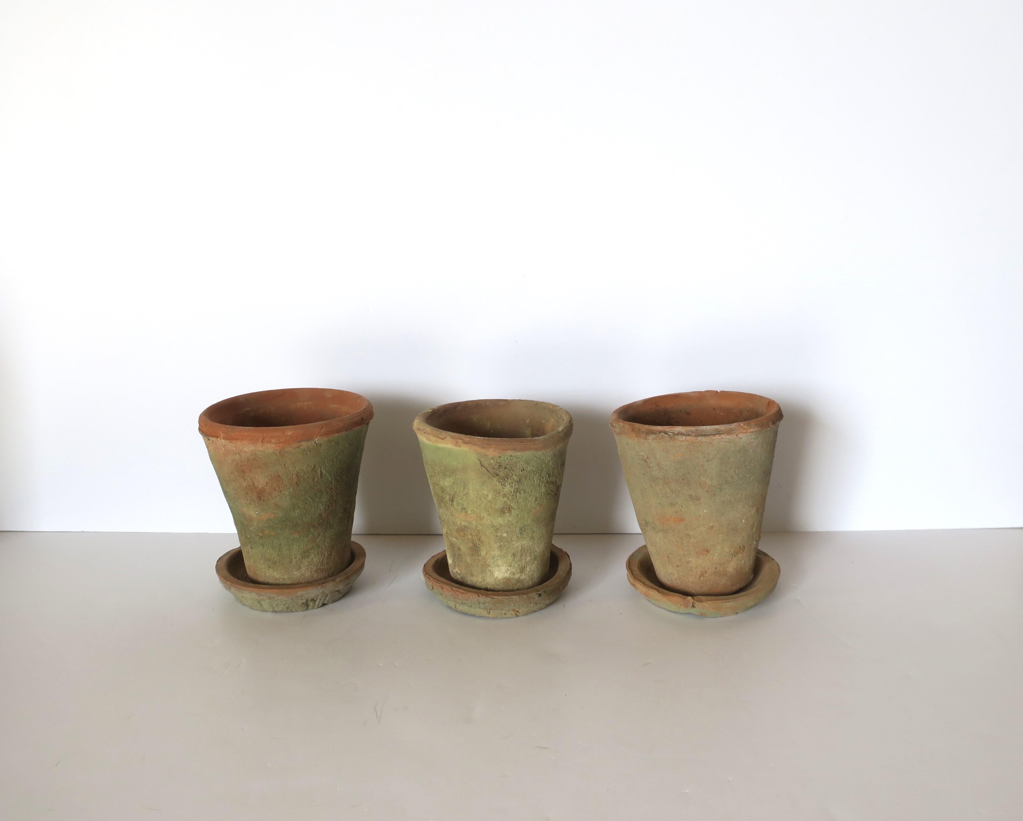 A beautiful set of three (3) thrown terracotta plant or flower-pot planters in an organic modern/rustic/minimalist design style. This set of three, each with underplate, and an organic nature to them are intentionally slightly irregular in shape and