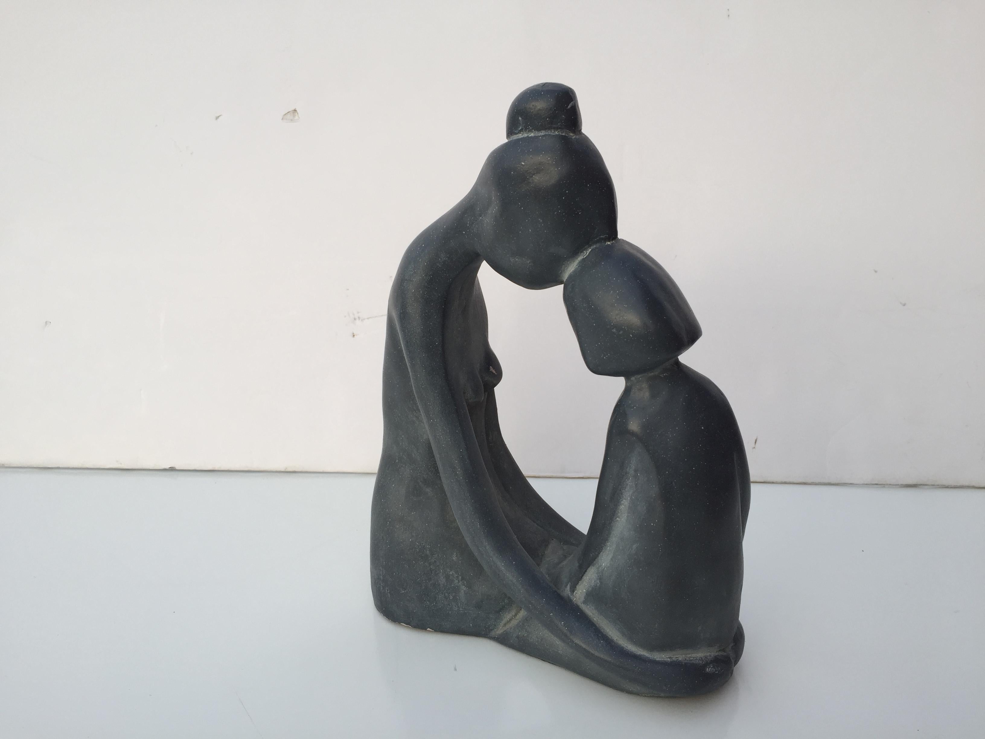 Small signed sculpture depicting mother and daughter duo  in poignant and graceful hold done in grayish blue.