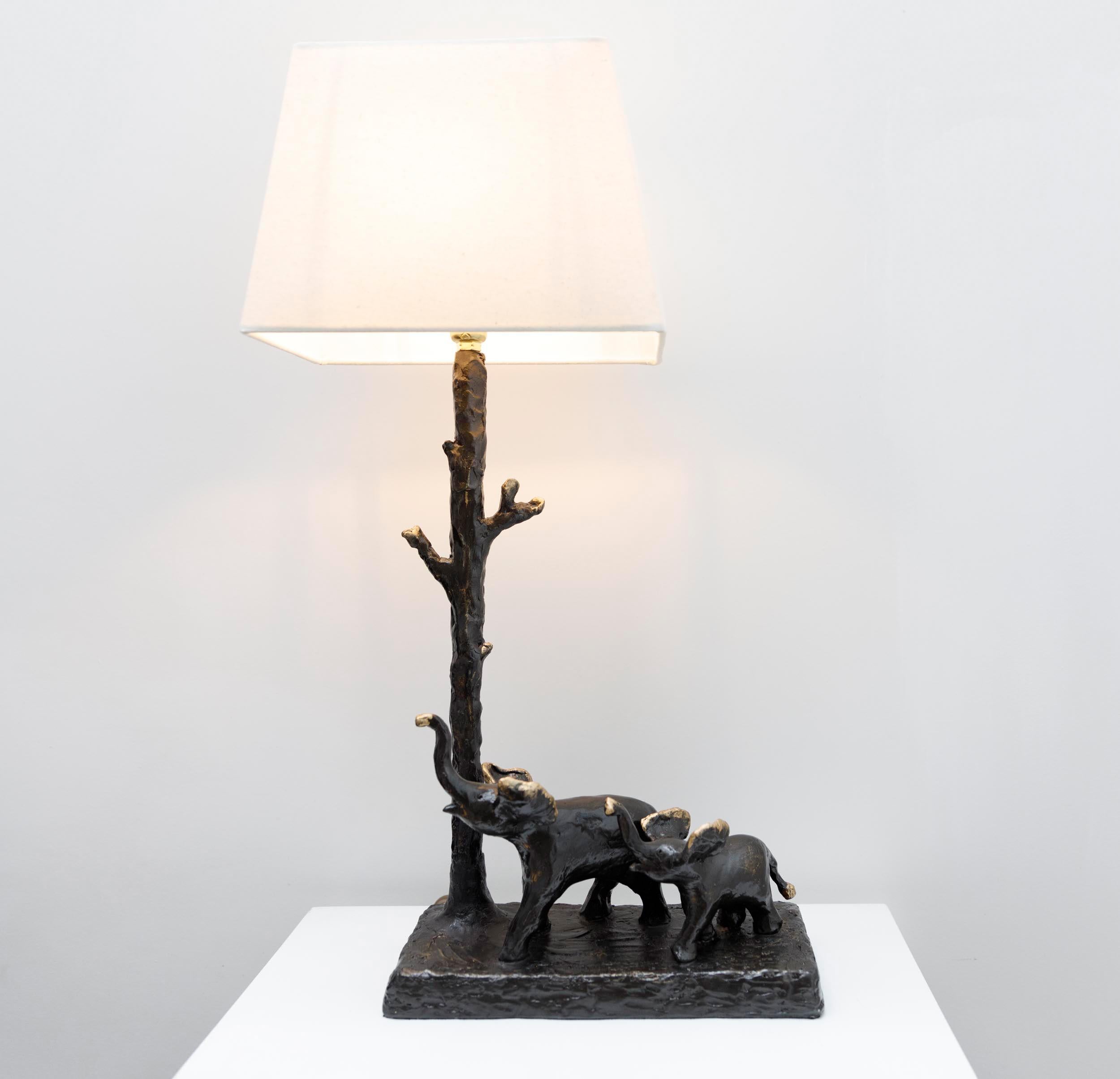Last in the series of resin cast sculptural table lamps, this one of a kind lamp of mother and baby elephant is  hand crafted molded and cast in resin.  A whimsical functional sculptural table lamp of elephants strolling along with their trunks