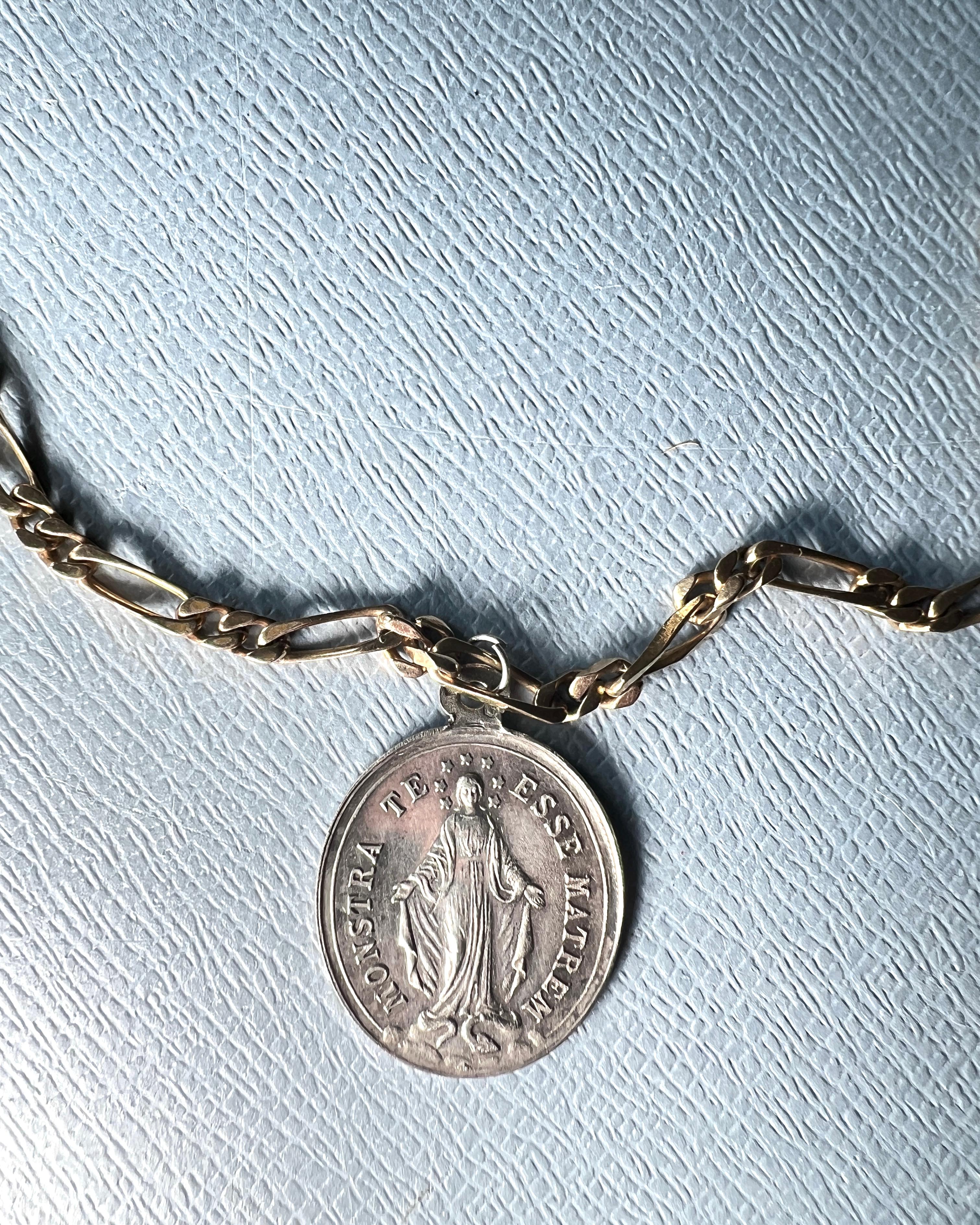 This entirely vintage French necklace features a solid silver Virgin Mary medal with the Latin inscription Monstra Te Esse Matrem — Show thyself as Mother. Sourced in Paris, the medal is suspended from a vintage gold-plated figaro chain, creating a