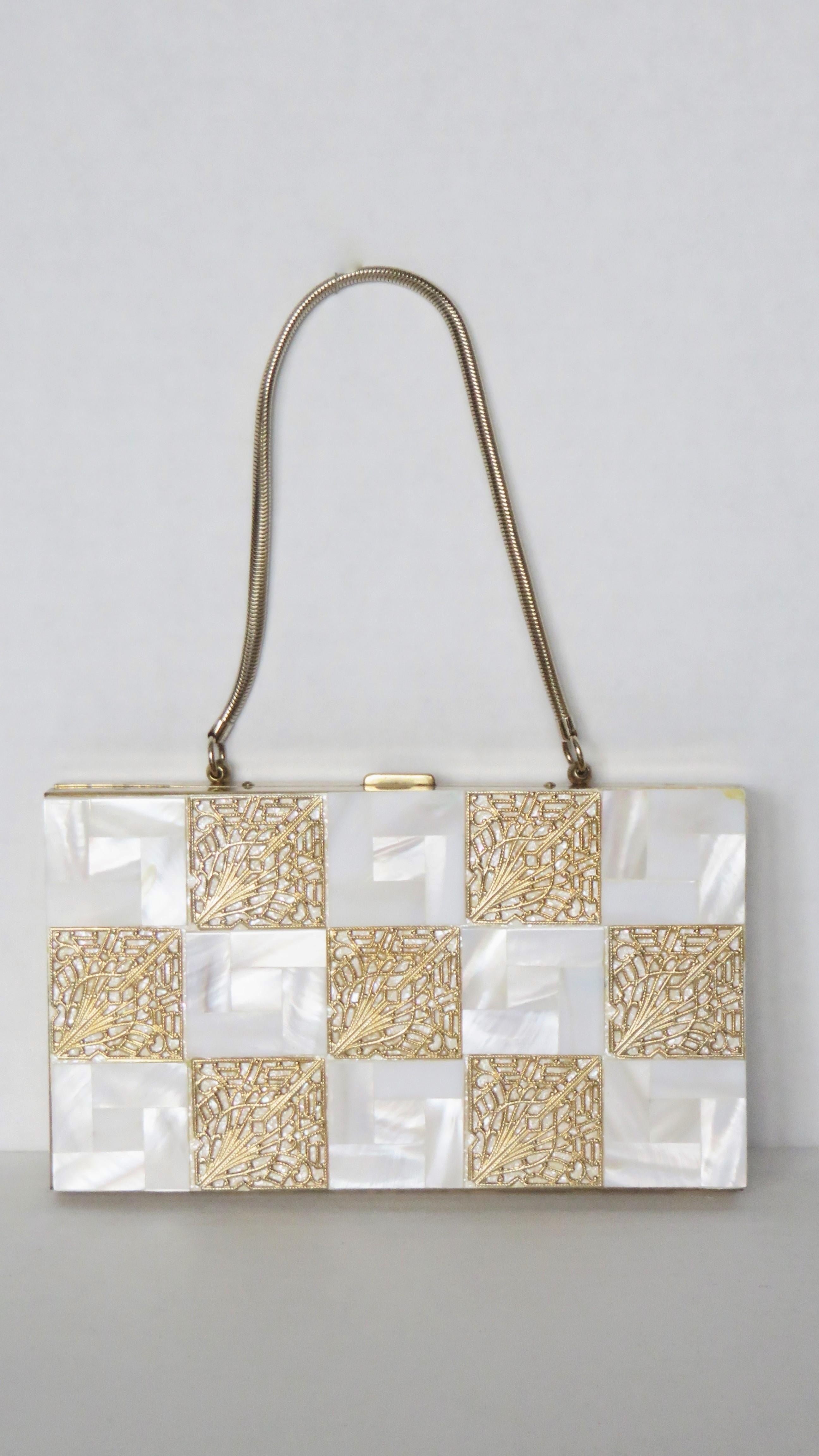 A gorgeous checker board pattern of mother of pearl and gold filigree compact purse, minaudiere with a white sparkle back.  It has a mesh snake chain top handle and press button opener to a mirror on one side and and a comb, powder and lipstick