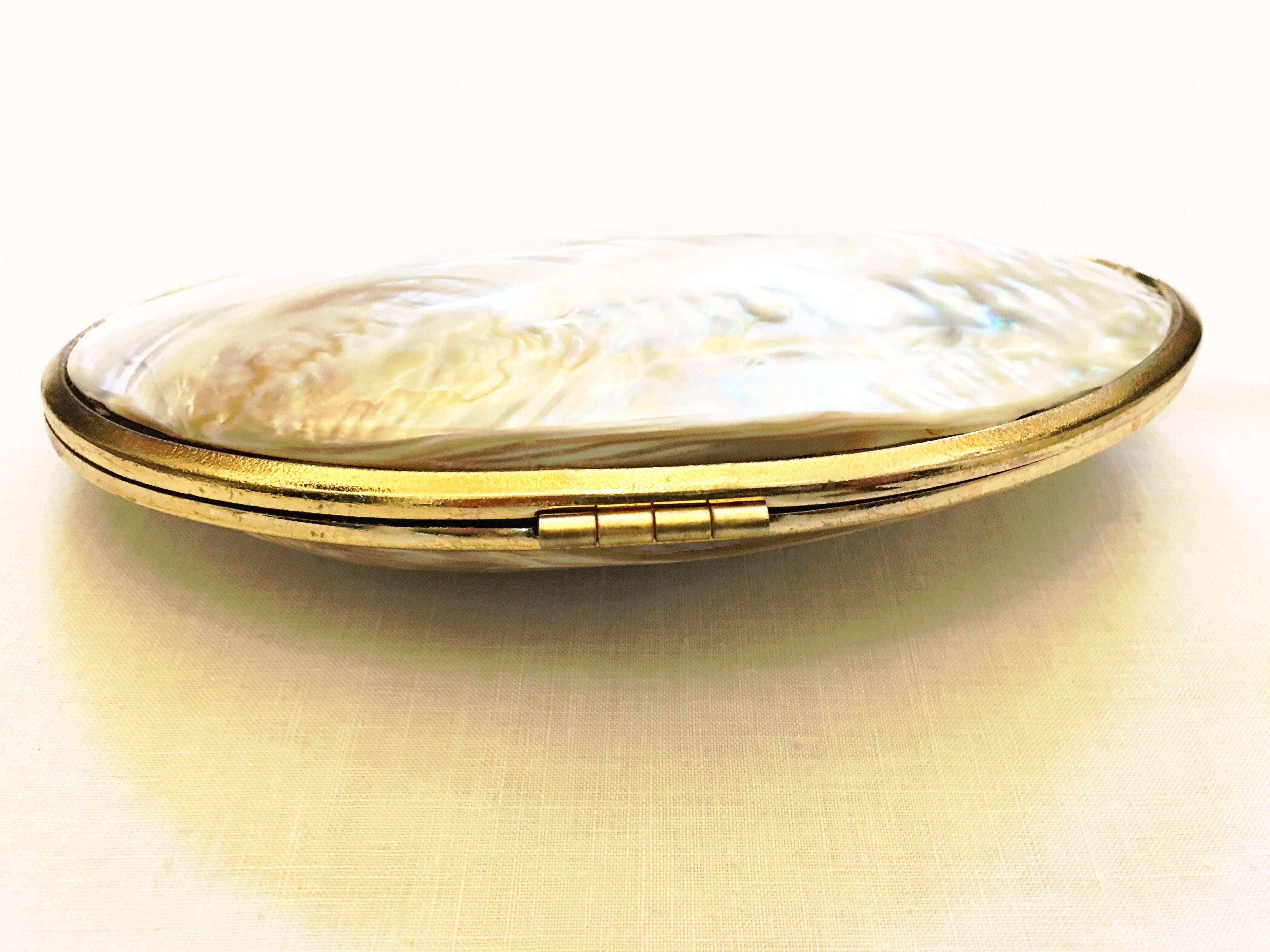 Very unique design for an evening bag with mother of pearl outer shell. Gold tone trim and clasp/hinge. Fully lined in chocolate brown fabric. Neutral color allows for it to be paired with almost any color or design. Can also be carried casually as