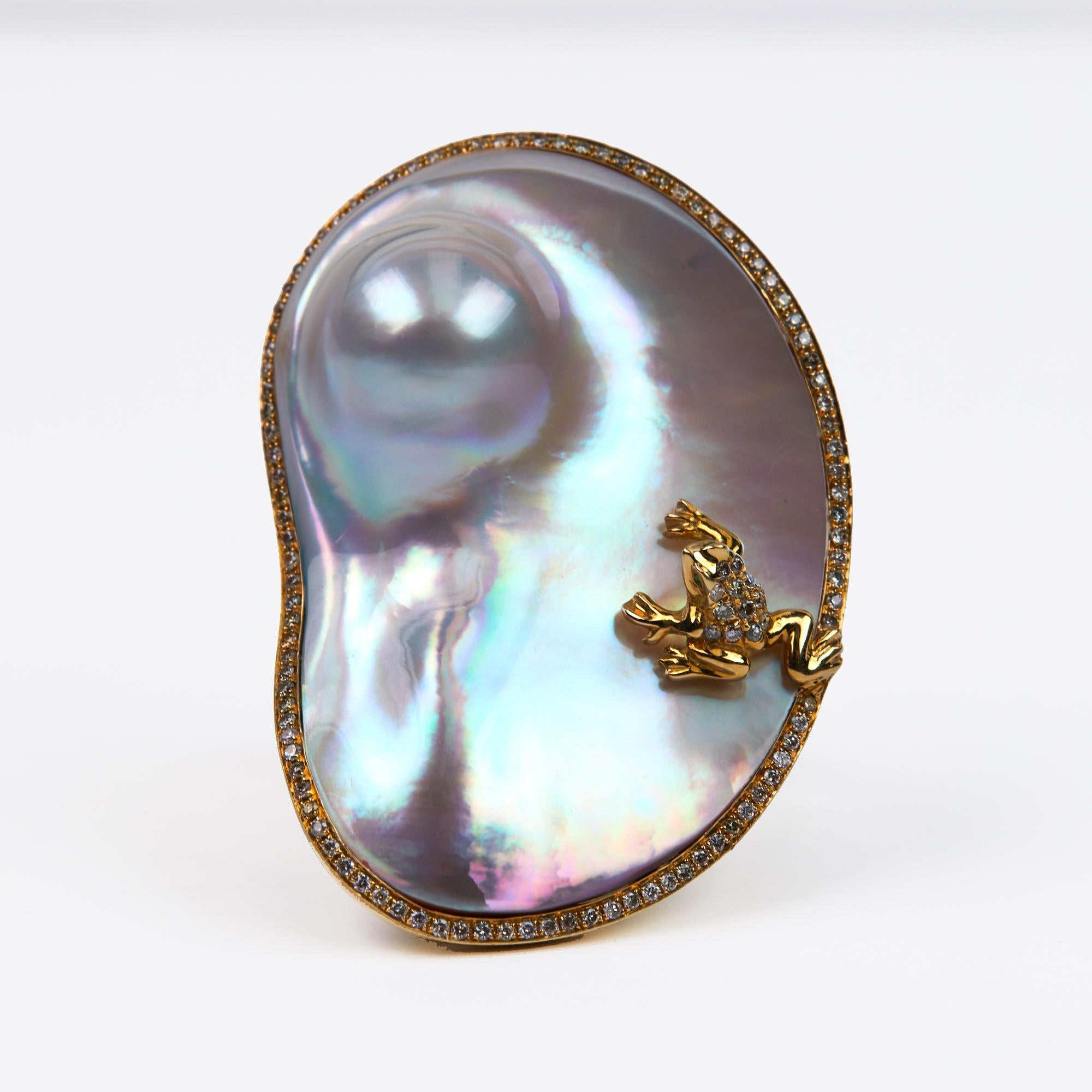 Mother Of Pearl Cocktail Ring with a frog made of diamonds.  This one of a kind Fashion Ring is sure to make an entrance with you. This unique and naturally shaped Mother of Pearl is lined in diamonds with a diamond and gold frog sitting on top. 