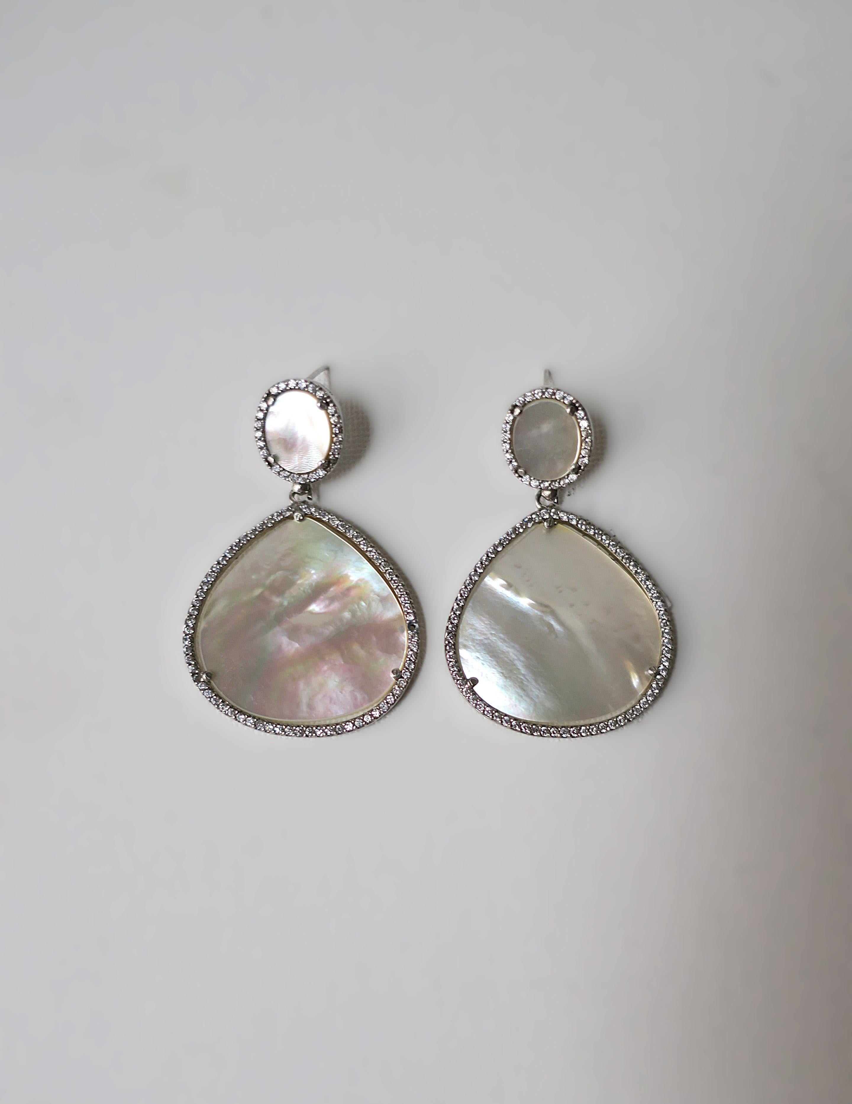 A pretty pair of Mother of Pearl, sterling silver, and diamond-esque (faux) dangle drop earrings. Sterling silver earring frame supports white mother of pearl, surrounded by faux diamonds. Backs marked '925' for sterling silver. A great pair to