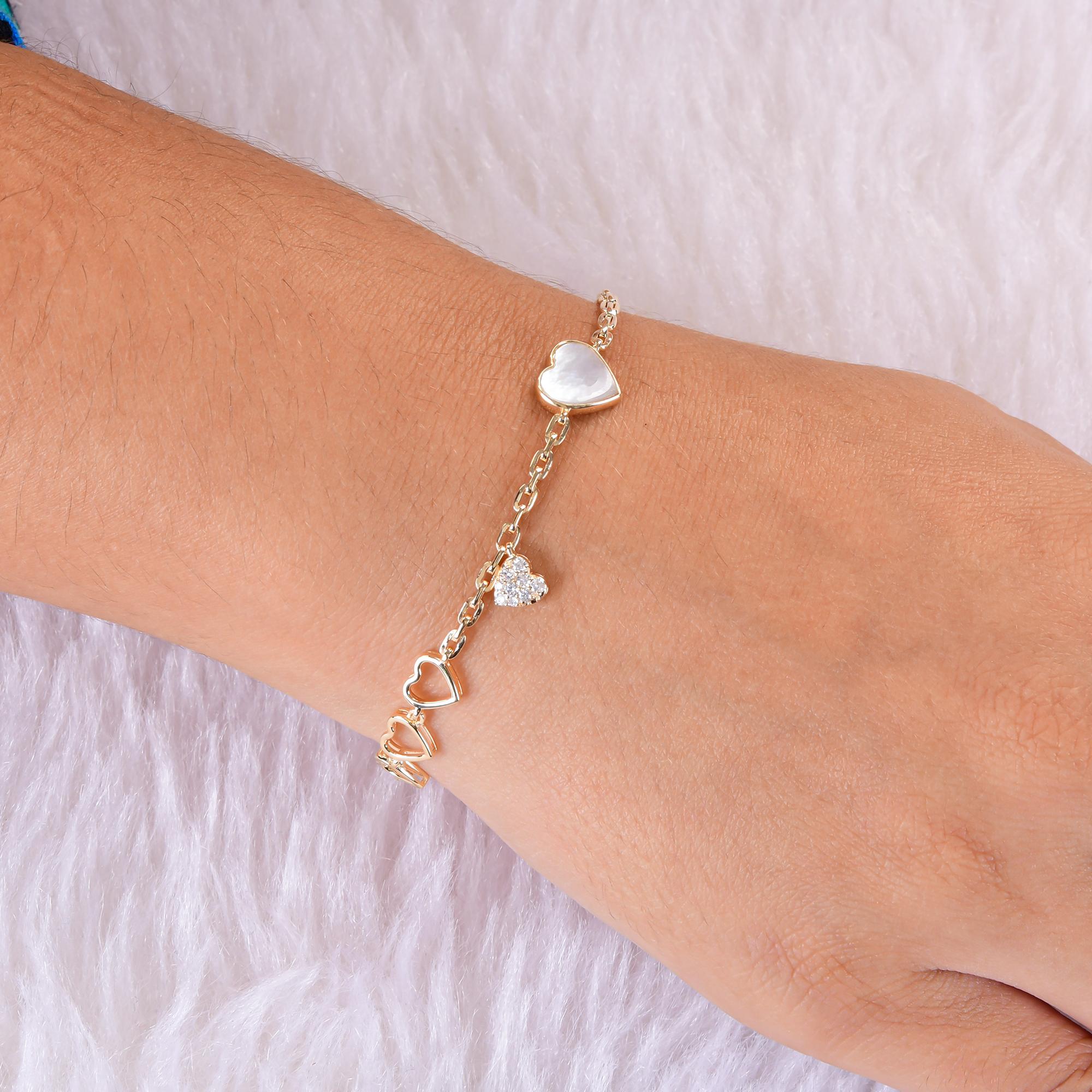 Ce cœur en nacre et diamant  Le bracelet à breloques en or jaune 18 carats se compose de trois cœurs ouverts en or montés en ligne, d'un cœur plus grand en nacre serti en chaton à l'opposé des cœurs et d'un cœur délicat serti de diamants qui pend le