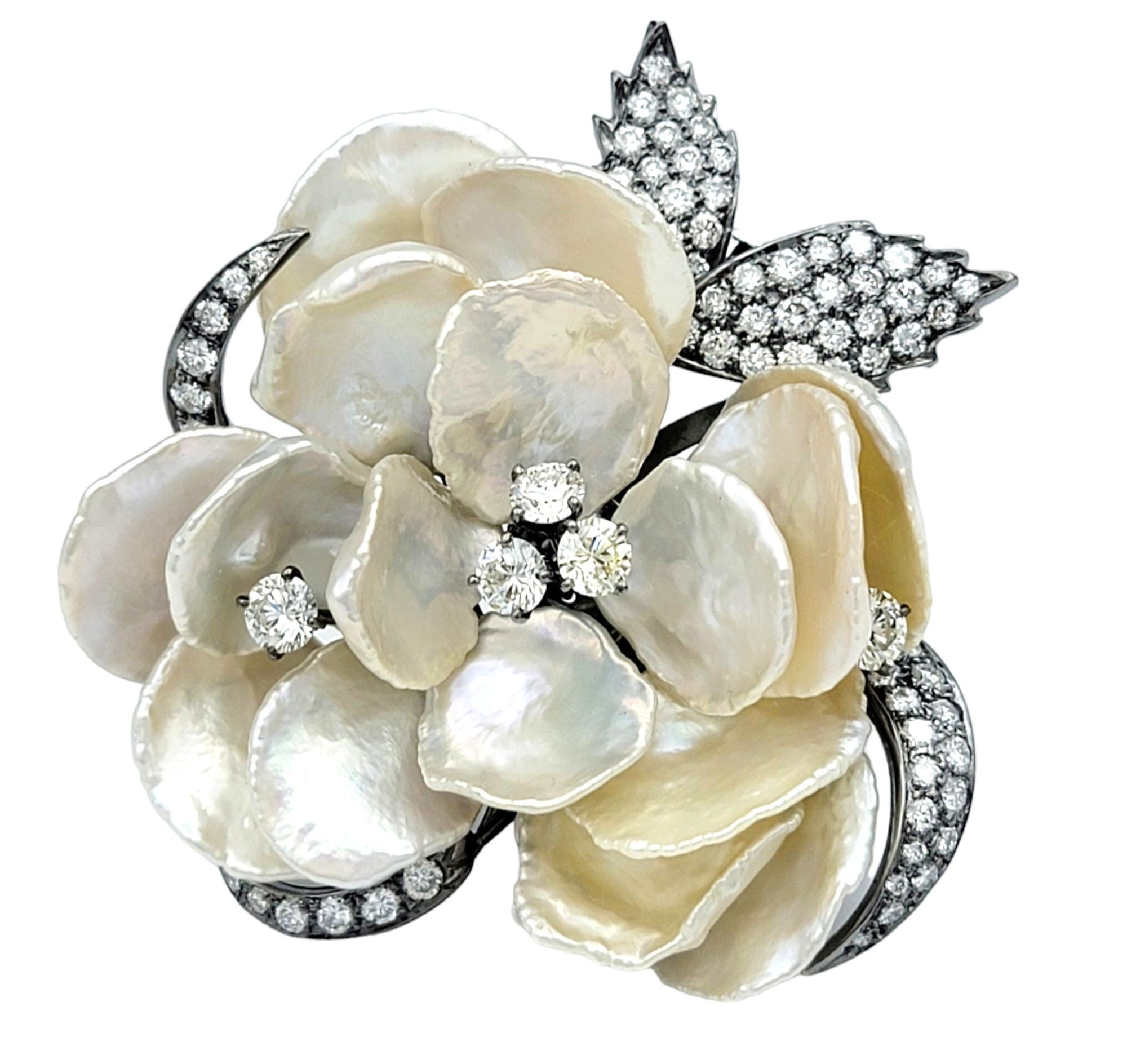 This stunning flower brooch features delicate petals crafted from lustrous mother of pearl, set in 18 karat white gold with black rhodium for a striking contrast. The leaves are adorned with sparkling diamonds, adding a touch of glamour and