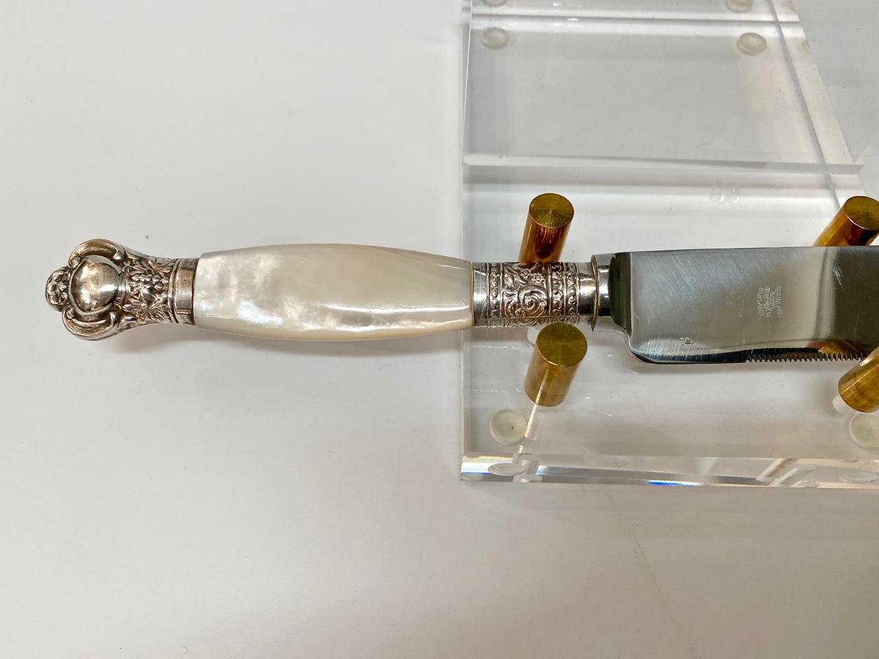 This is a beautiful example of a mother of pearl handled cake or possibly carving knife. The knife is detailed with a sterling collar and finial. The stainless steel blade is in very good condition. This would make a beautiful wedding cake knife.