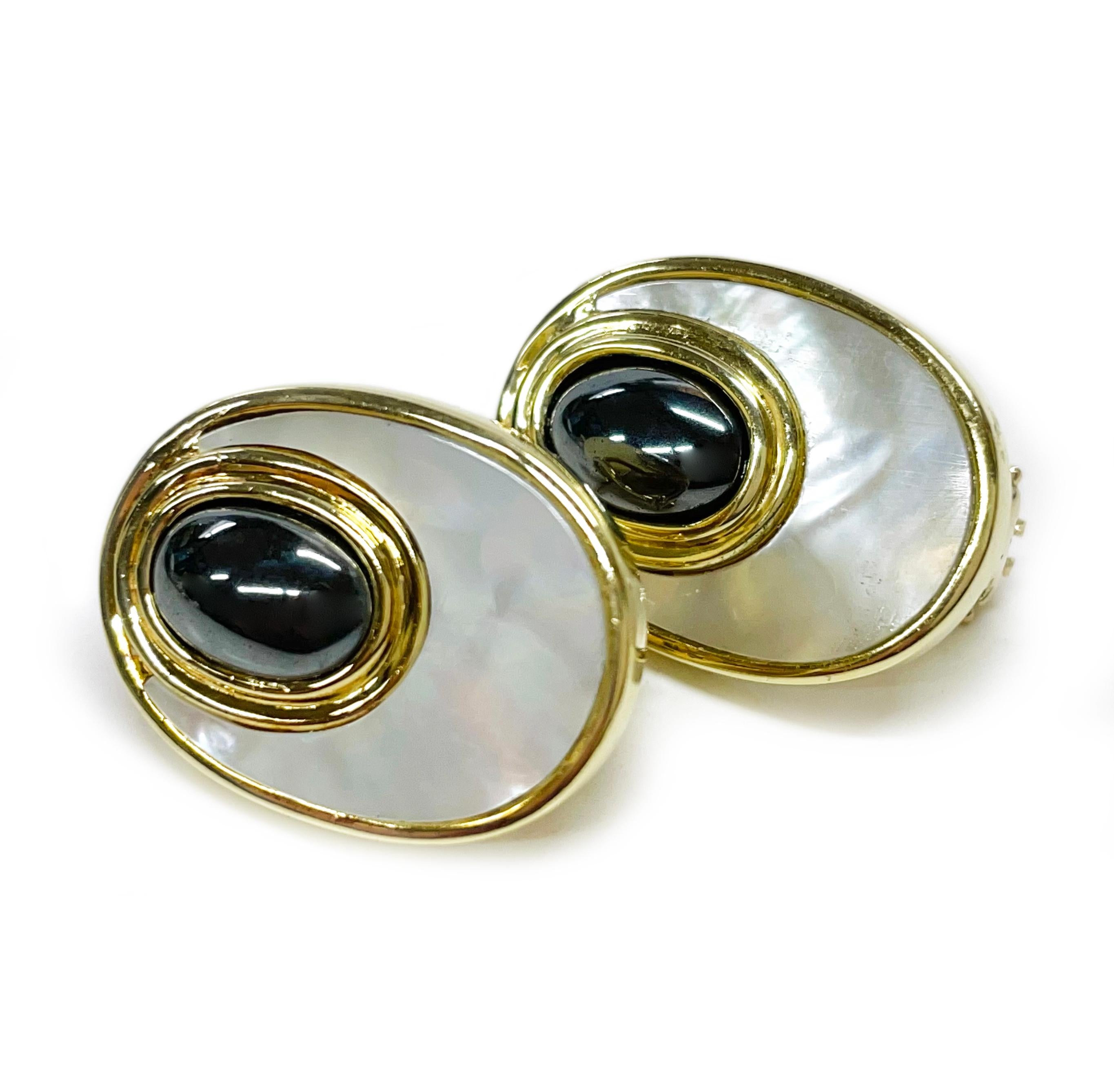 14 Karat Mother of Pearl Hematite Earrings. The earrings feature a double bezel, the larger bezel has flat mother of pearl while the smaller oval bezel has a 9 x 6mm hematite cabochon. The earrings have a post and Omega clip back. Each earring