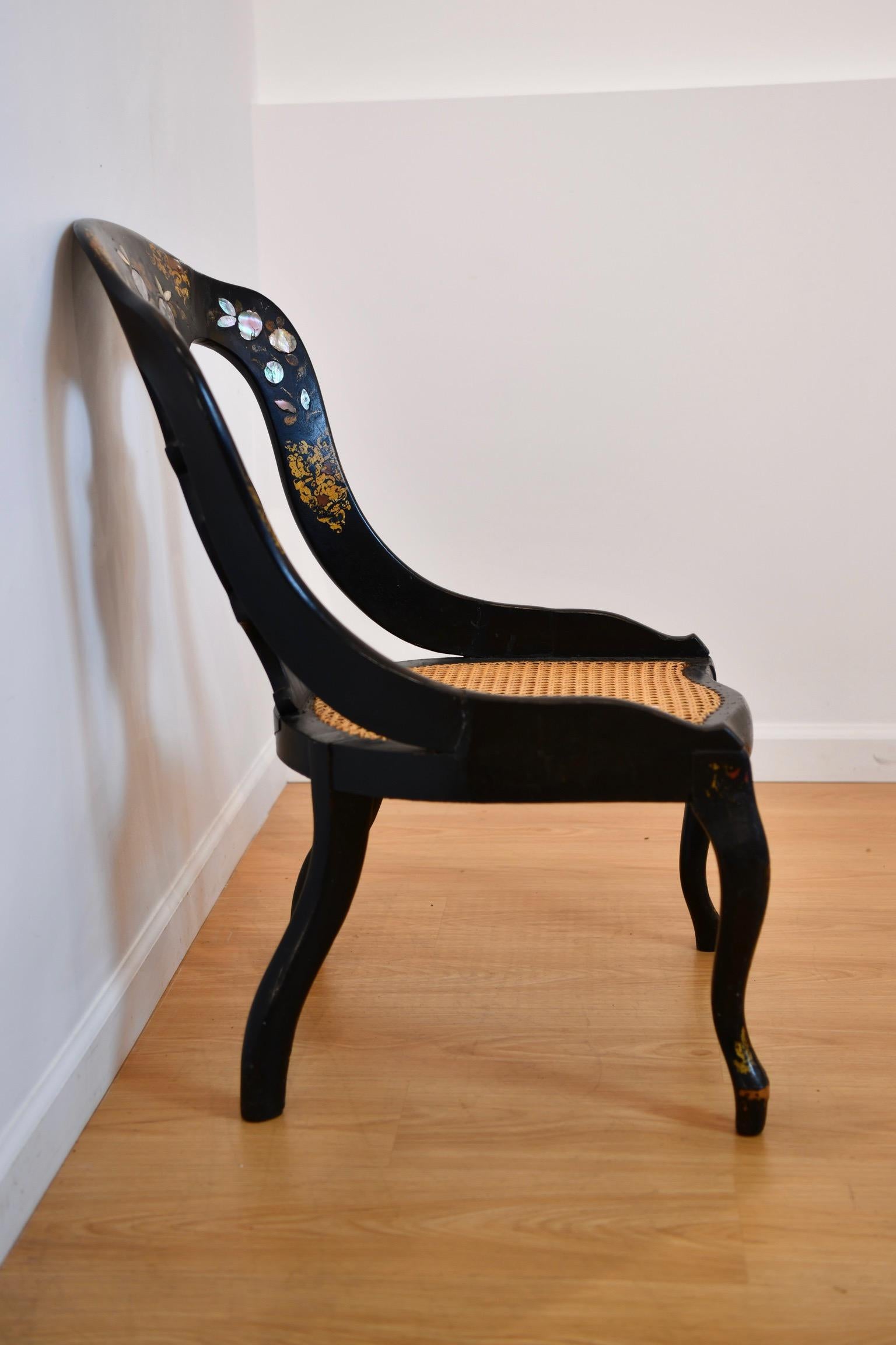 Chaise cannée avec incrustation de nacre et peinture dorée sur le dossier. Peinture décolorée sur les pieds ; probablement récemment ré-encadrée. Dimensions : 33 