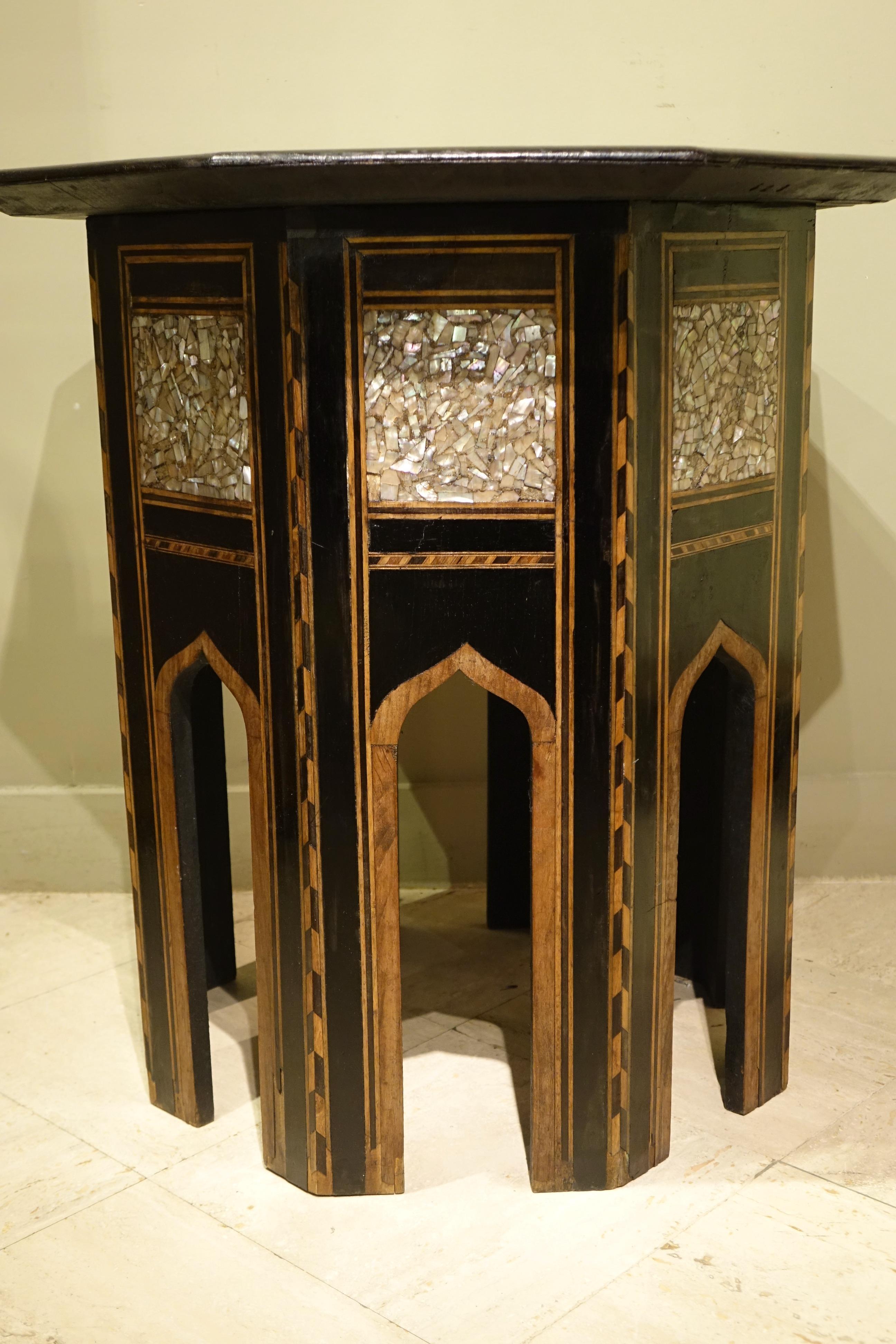 Grande table d'appoint octogonale avec incrustation de nacre sur le plateau et sur les bords, au-dessus des mirhabs façonnés et formant la base.
Riche incrustation de nacre avec une étoile à huit branches, avec une calligraphie au centre d'une