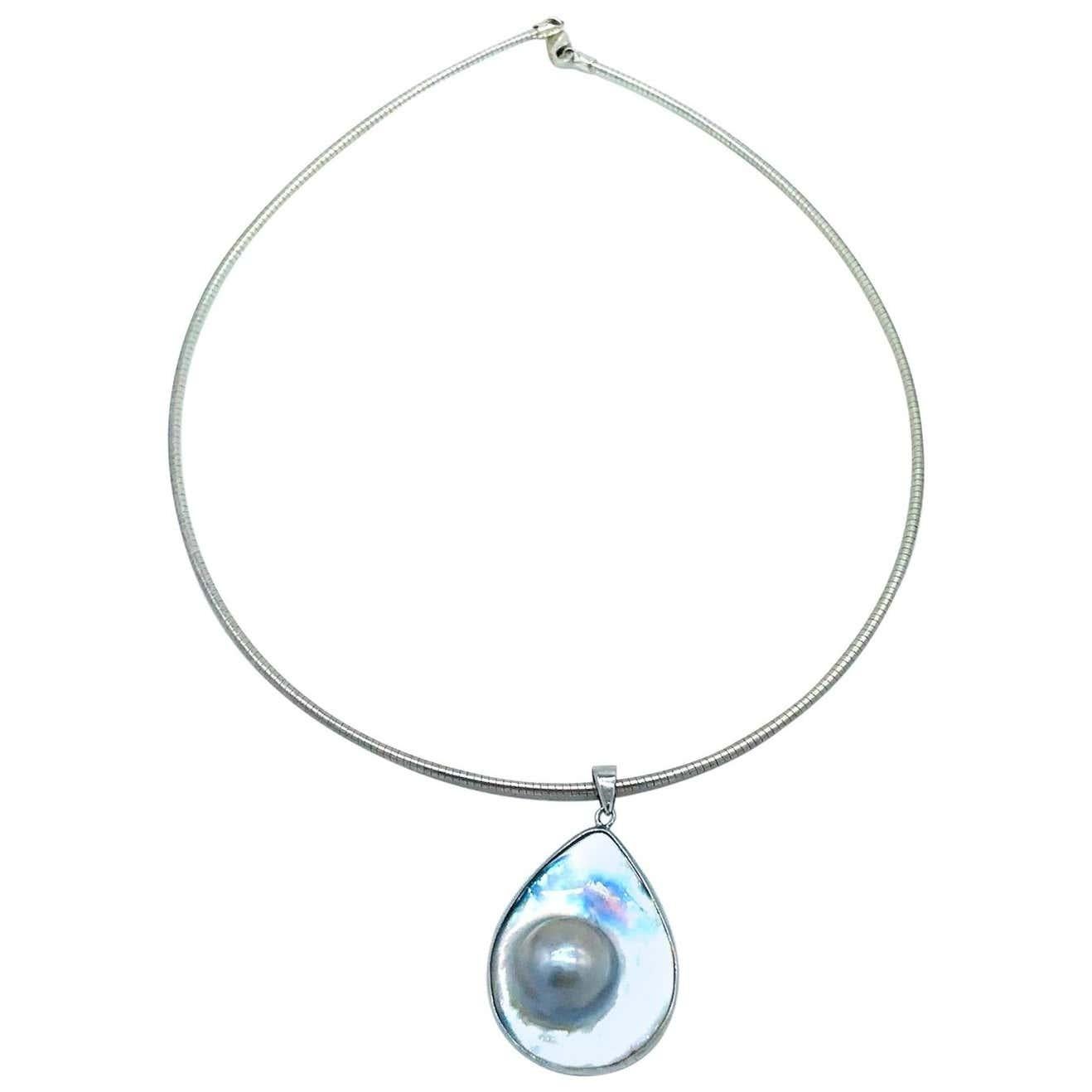 Nacre, fil de fer pour collier de perles Mobee, pendentif
Gris lumineux, perle sertie dans une goutte en forme de poire de près de 1-3/4 x 1 pouce, sertie dans une lunette.
Le fil de cou est un fil arrondi de 1,90 mm, d'une longueur de 18