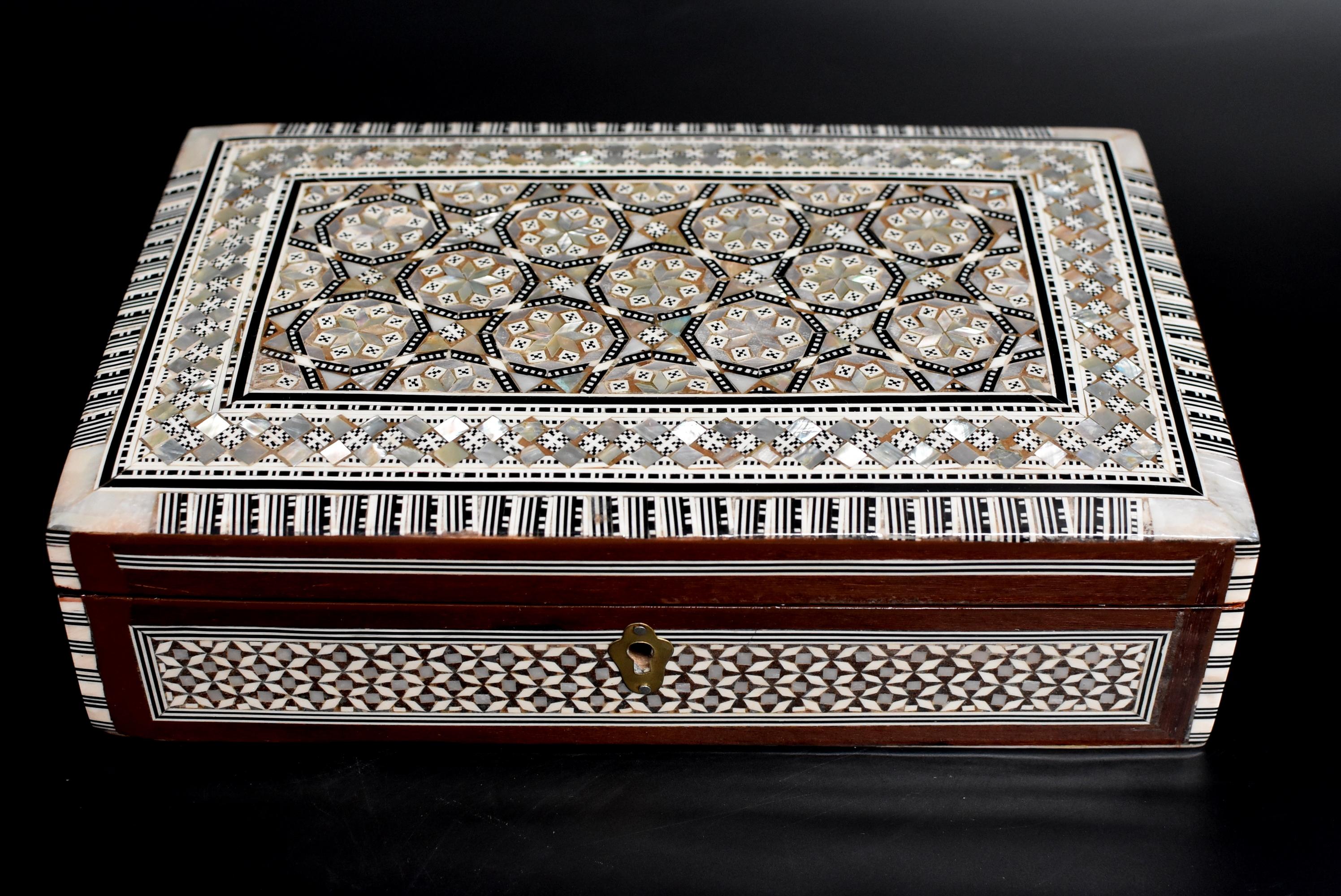 Encrusted with genuine mother of pearl, this beautiful box has an intricate star and ribbon design in a beehive grouping. Luxurious iridescence created by fine craftsmanship. A work of art. Lined with red felt. Handmade.

 