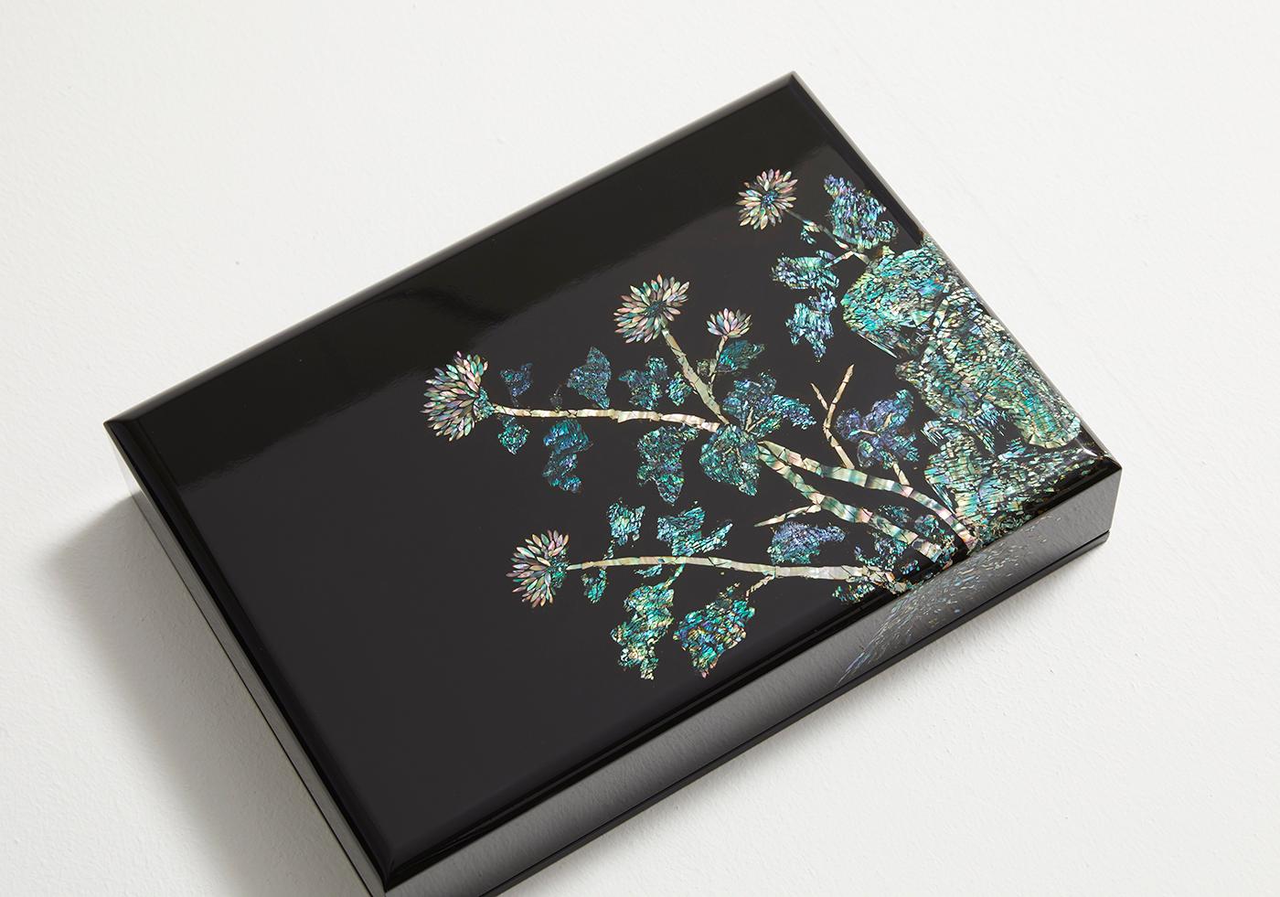 This artwork applied the method of striking and scouring to the carefully selected pieces of the iridescent mother of pearl, to create a wooden box depicting chrysanthemum flowers, one of the four gracious plants symbolizing strong integrity and