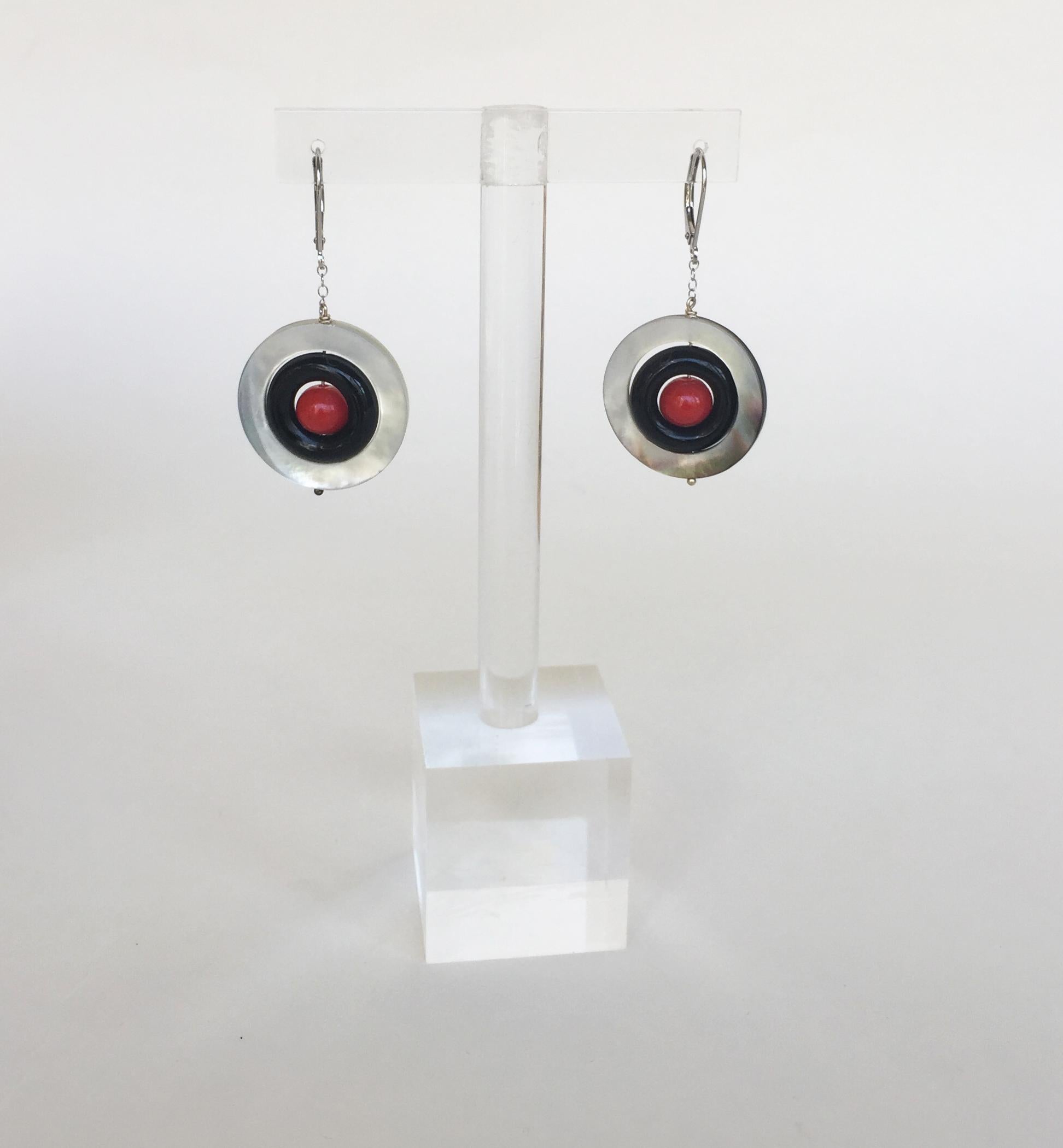 These mother of pearl, onyx, and coral earrings with 14k white gold lever backs and chain are striking. Starting with a ring of iridescent mother of pearl, these earrings have a modern twist with black onyx and bright red coral at the center. The