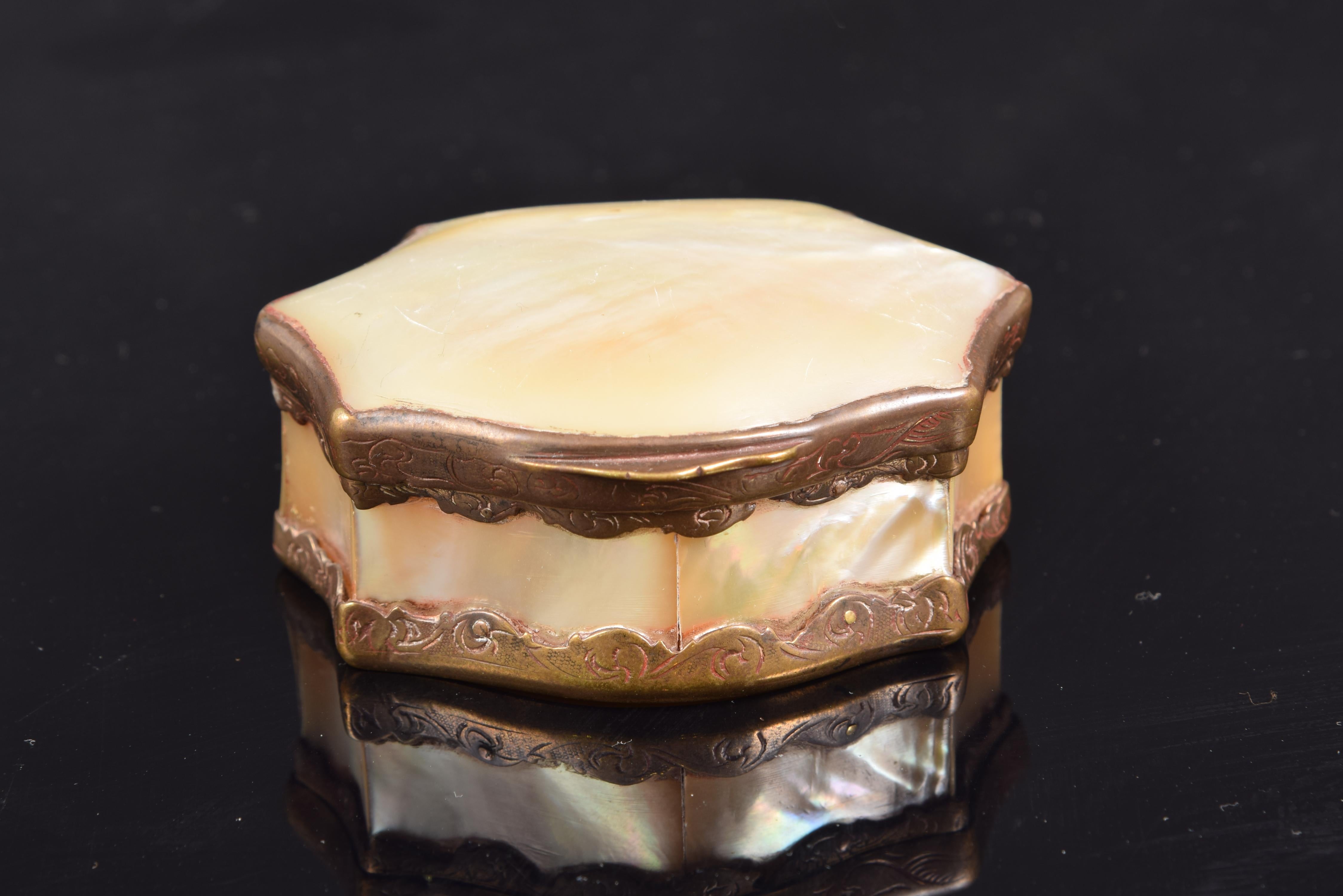 Mother of pearl box with bronze frame, 19th century.
Box made of mother of pearl plates joined thanks to a bronze structure decorated with simple plant elements and which still has traces of gilding in some areas. The shape of the piece would
