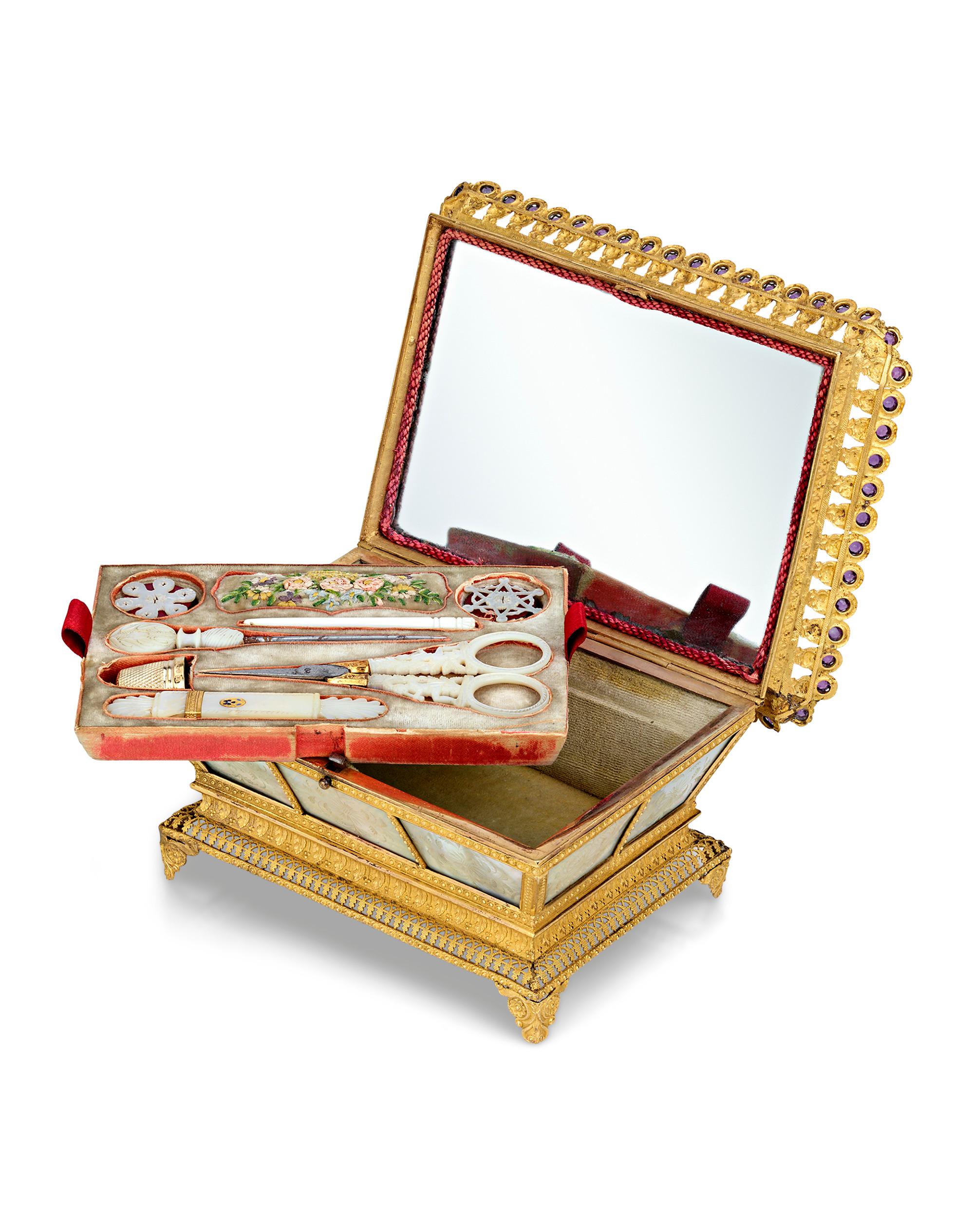 This captivating Palais Royal sewing nécessaire is crafted of engraved mother of pearl mounted in rich doré bronze. The hinged box contains a removable tray lined with velvet that holds an assortment of exquisitely decorated mother-of-pearl and gilt