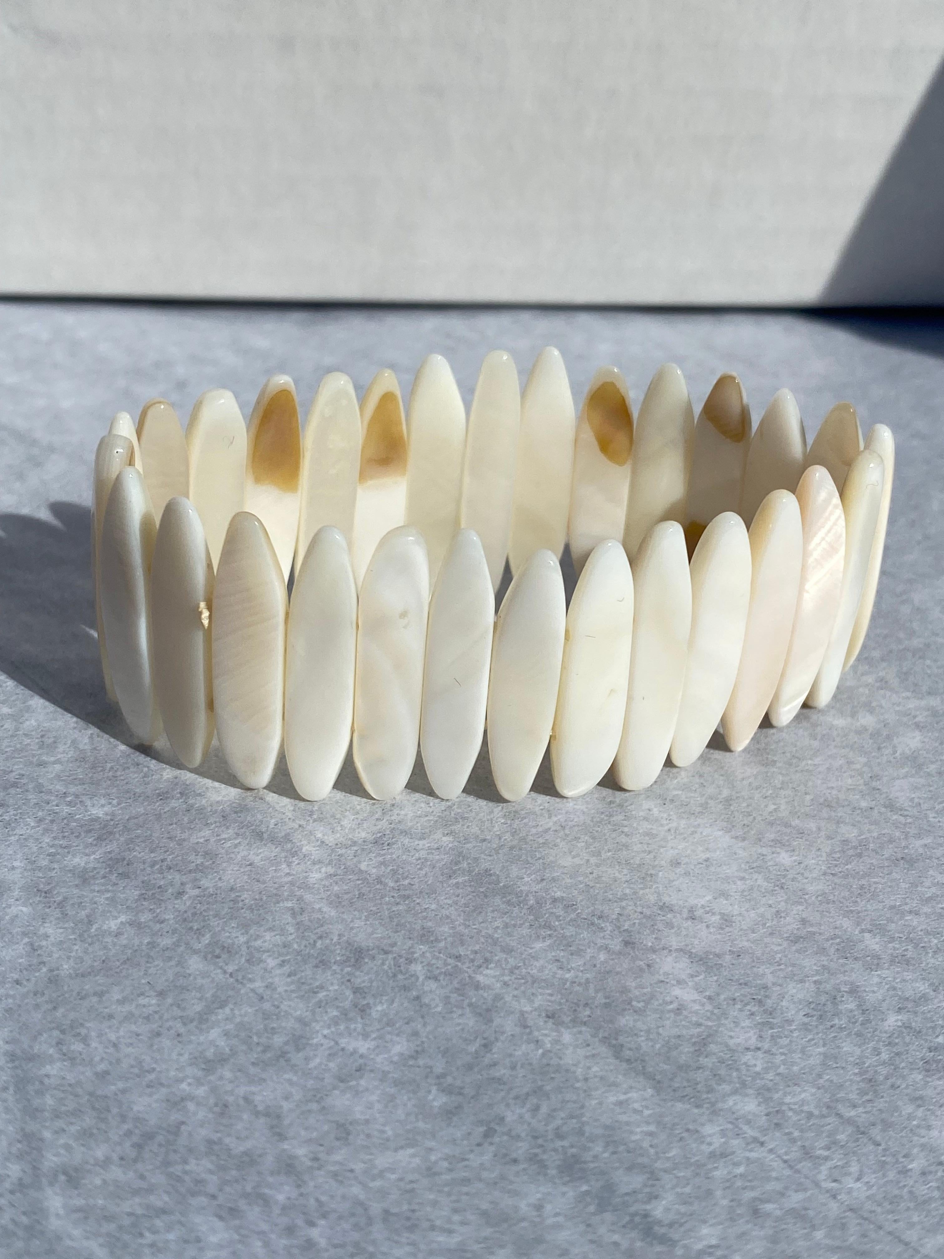 Mother of Pearl, Expandable Hand Cut Bracelet 
Luminesce, white colored measuring 1 inch long an 6.5 mm wide. The mother of pearl shells are set in a double row of elastic to expand this bracelet. GIA Gemologist inspected and evaluated