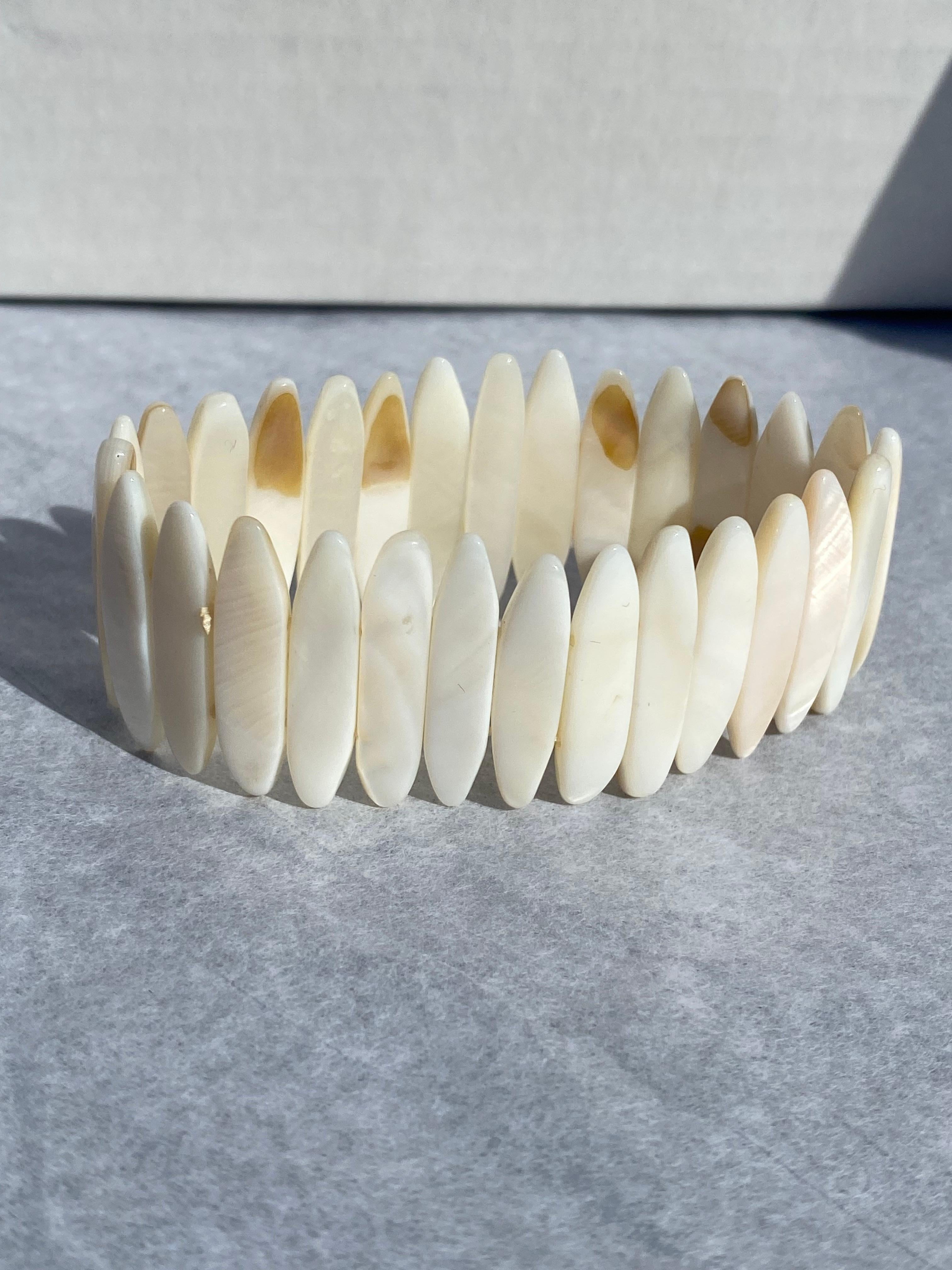 Perlmutt, dehnbares, handgeschnittenes Armband 
Luminesce, weiß gefärbt, 1 Zoll lang und 6,5 mm breit. Die Perlmuttmuscheln sind in eine doppelte Reihe von Gummibändern eingefasst, um dieses Armband zu erweitern. GIA Gemologist inspiziert und