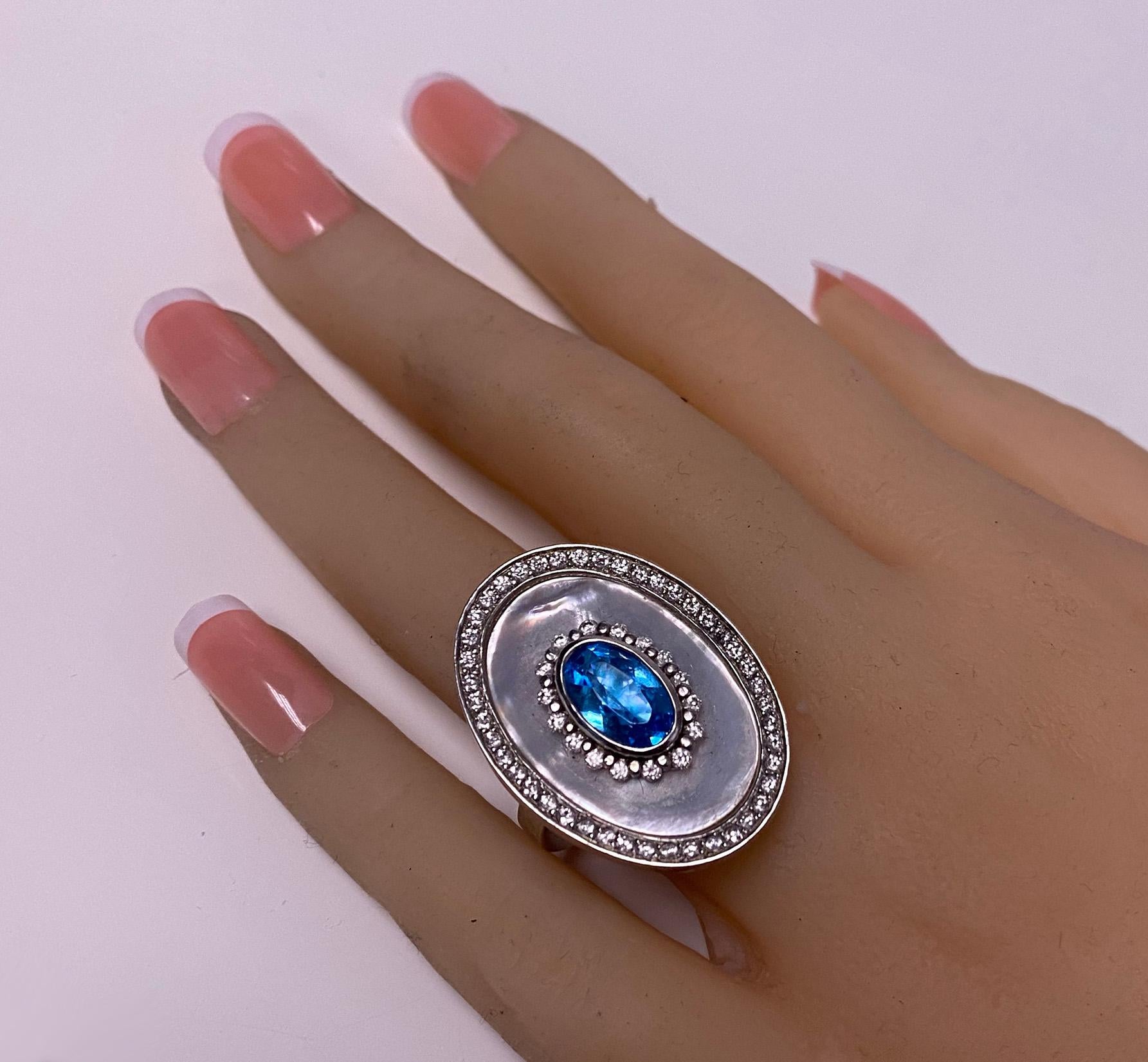 18K white gold blue Topaz, Diamond and mother of pearl custom made Ring. The Ring set with an oval facetted cut Blue Topaz, the mount of two diamond set borders surround topaz and mother of pearl respectively , approximately 1.09ct, total diamond
