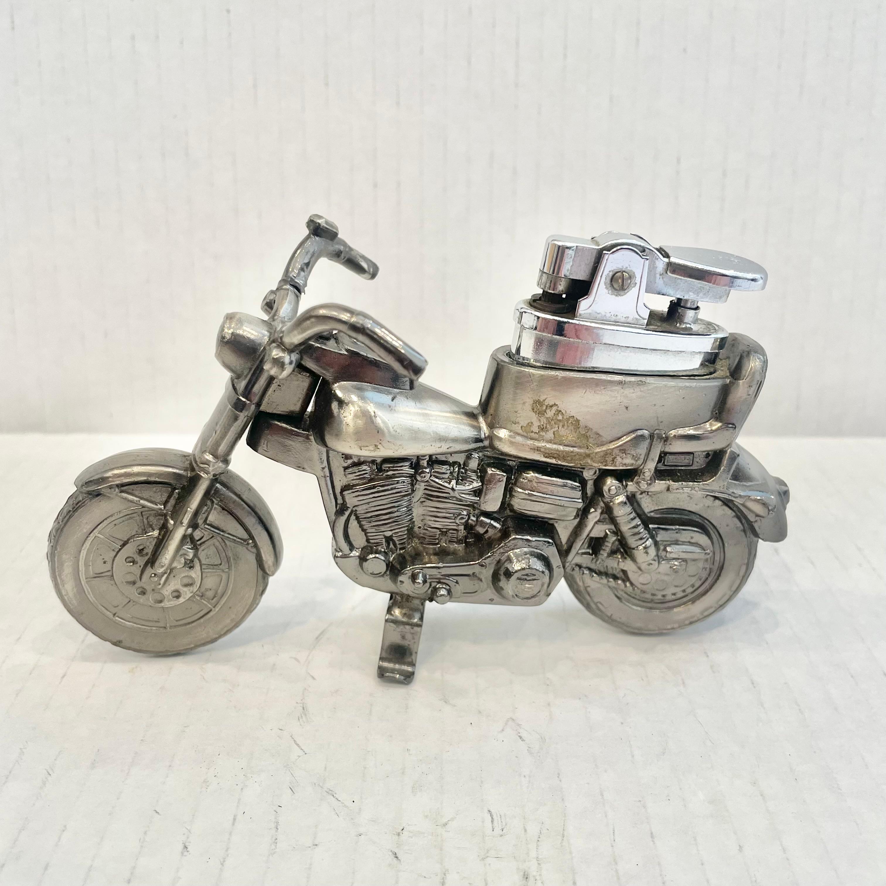 Cooles Vintage-Tischfeuerzeug in Form eines Motorrads. Vollständig aus Metall mit einem hohlen Körper. Schöne brünierte Silber Farbe mit komplizierten Details. Ein cooles Accessoire für den Tabakkonsum und ein Stück Unterhaltung. Leichteres