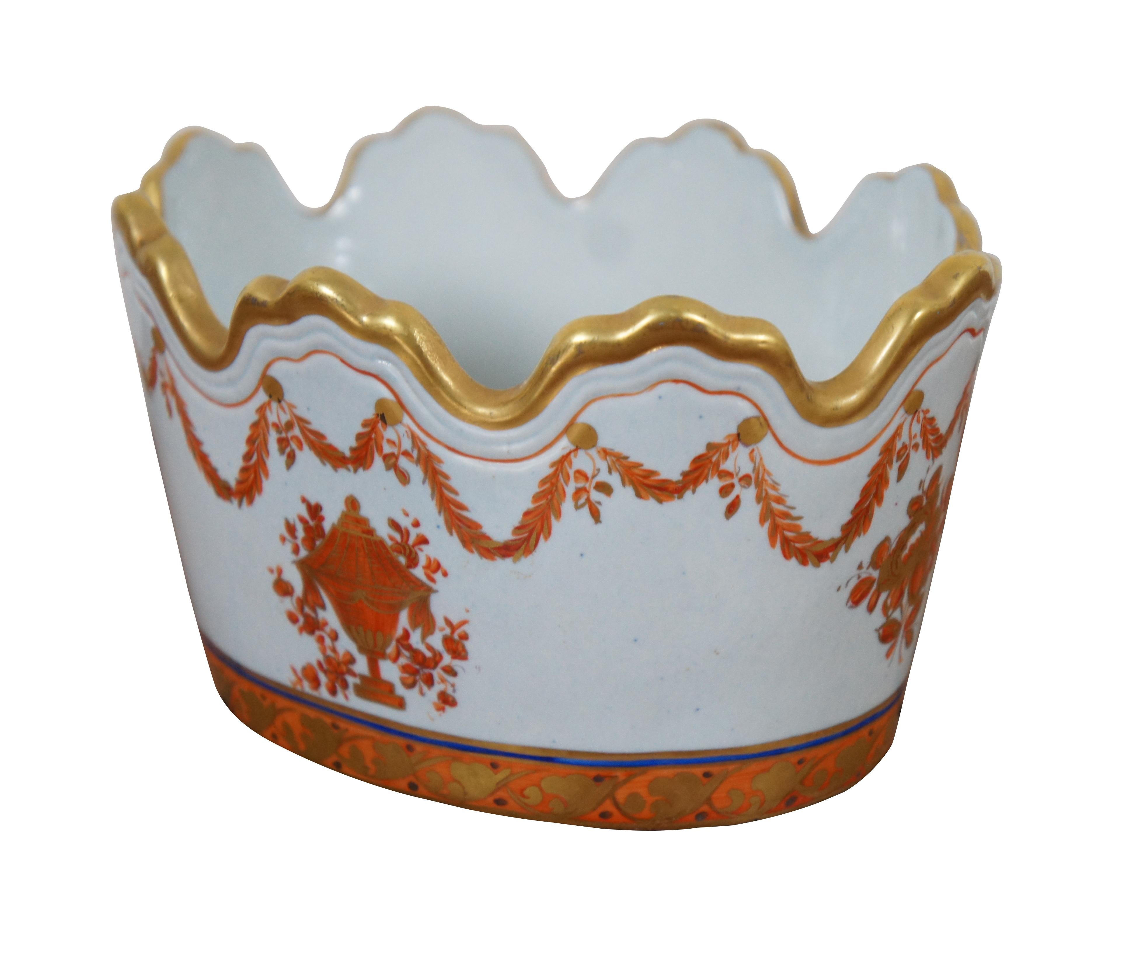 Lowestoft Reproduction Monteith nut / candy dish / cachepot by Mottahedeh featuring an oval form with gilded scalloped crown shaped edge and painted with orange neoclassical foliage with central trophy urn and cobalt blue band. Measure: 6