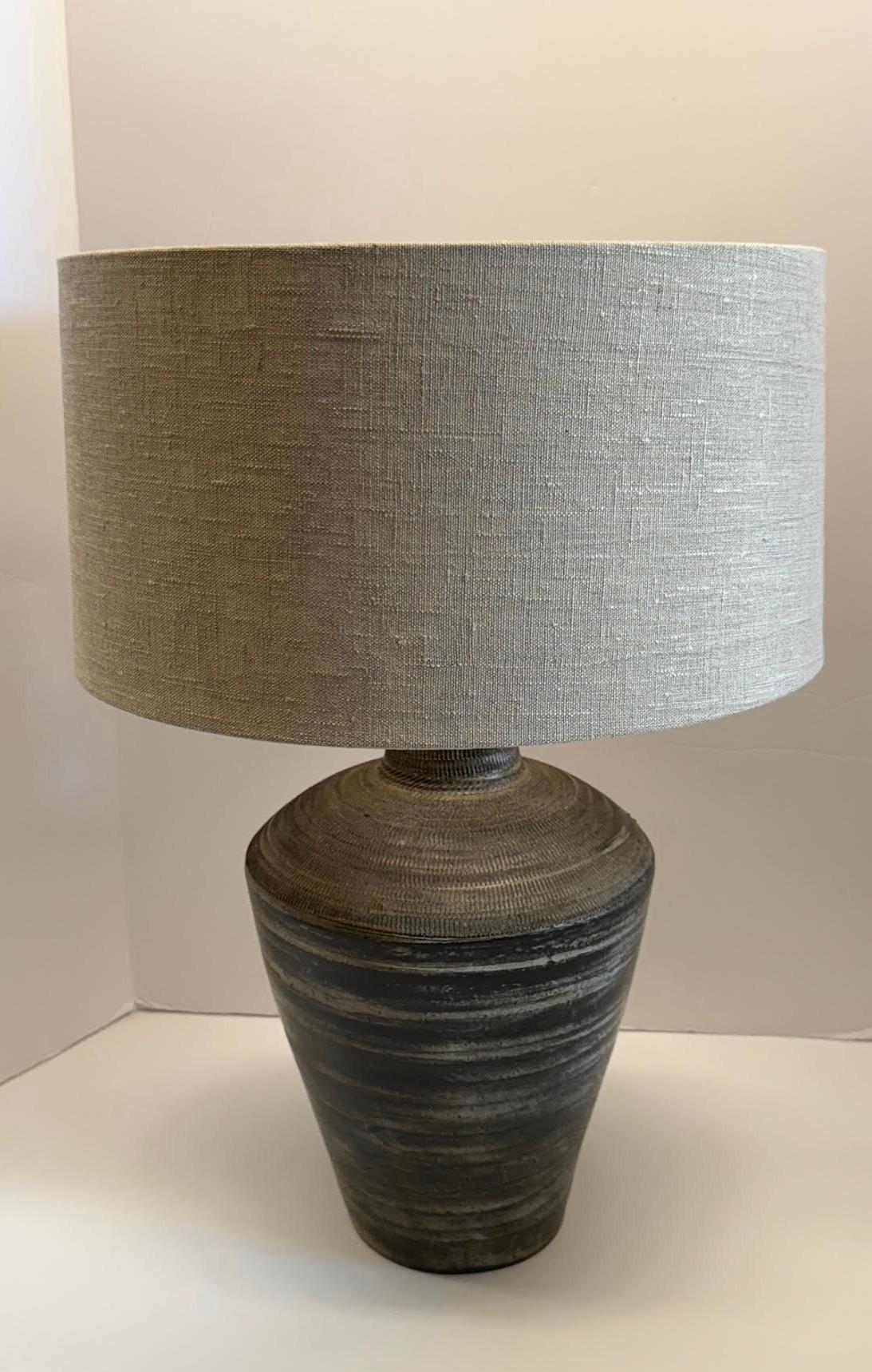 Contemporary Chinese pair textured mottled black ceramic lamps.
Horizontal decorative ridged detailing.
Weathered patina.
Tapered shape.
New Belgian linen shades included.
Base measures 9.5 