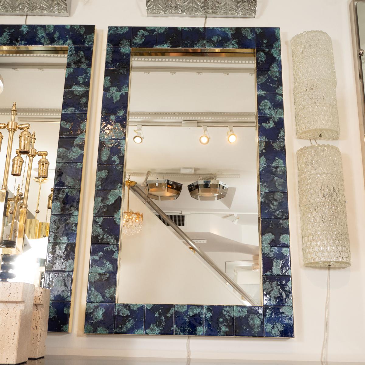 Brass framed mirror featuring mottled blue ceramic tile surround.