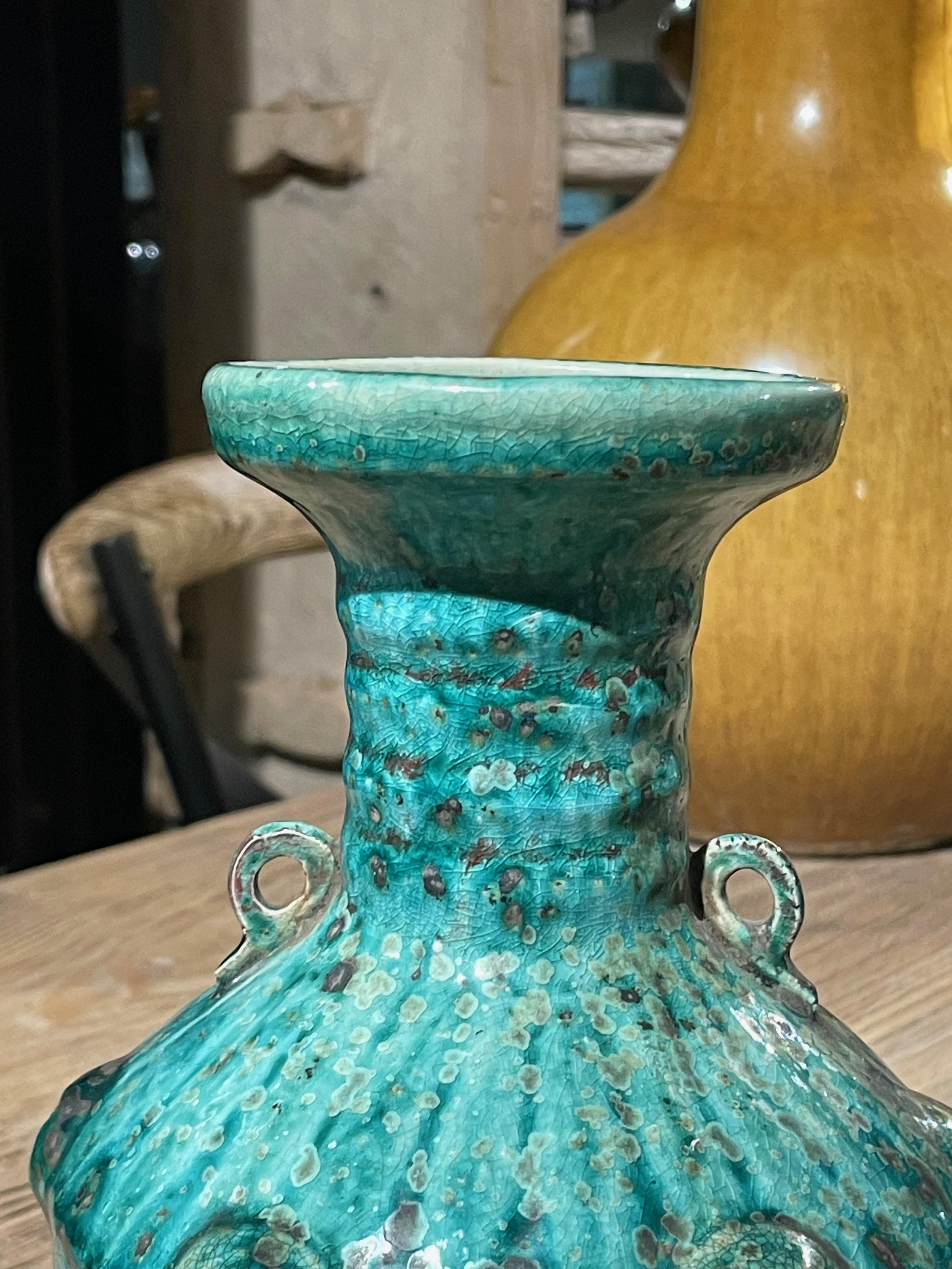 Contemporary Chinese mottled turquoise coloring with crackle glaze vase.
Horizontal rib texture design at neck of vase.
Two small handles.
Raised vertical pattern defining sections of the vase.
Dimpled textured overall design.
Two available and sold
