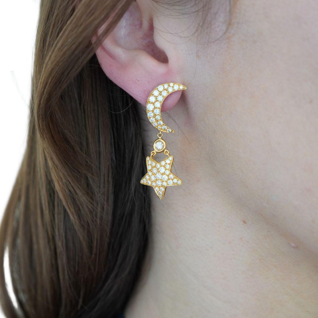 Questi orecchini vintage di Mouawad sono caratterizzati da un disegno celeste realizzato in oro giallo 18 carati, con il timbro 750, Mouawad e il marchio del produttore. Ogni orecchino presenta una mezzaluna con diamanti rotondi taglio brillante,