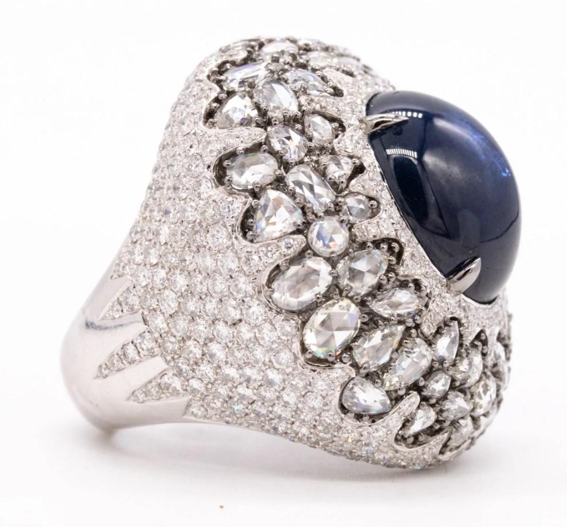Gorgeous cocktail ring designed by Mouawad.

impressive and very unique piece crafted in solid 18 karats of polished white gold.

Is mounted in the center, with an oval double cabochon cut (15.2 x 13.1 x 6.5 mm) of a natural blue sapphire of 13.90