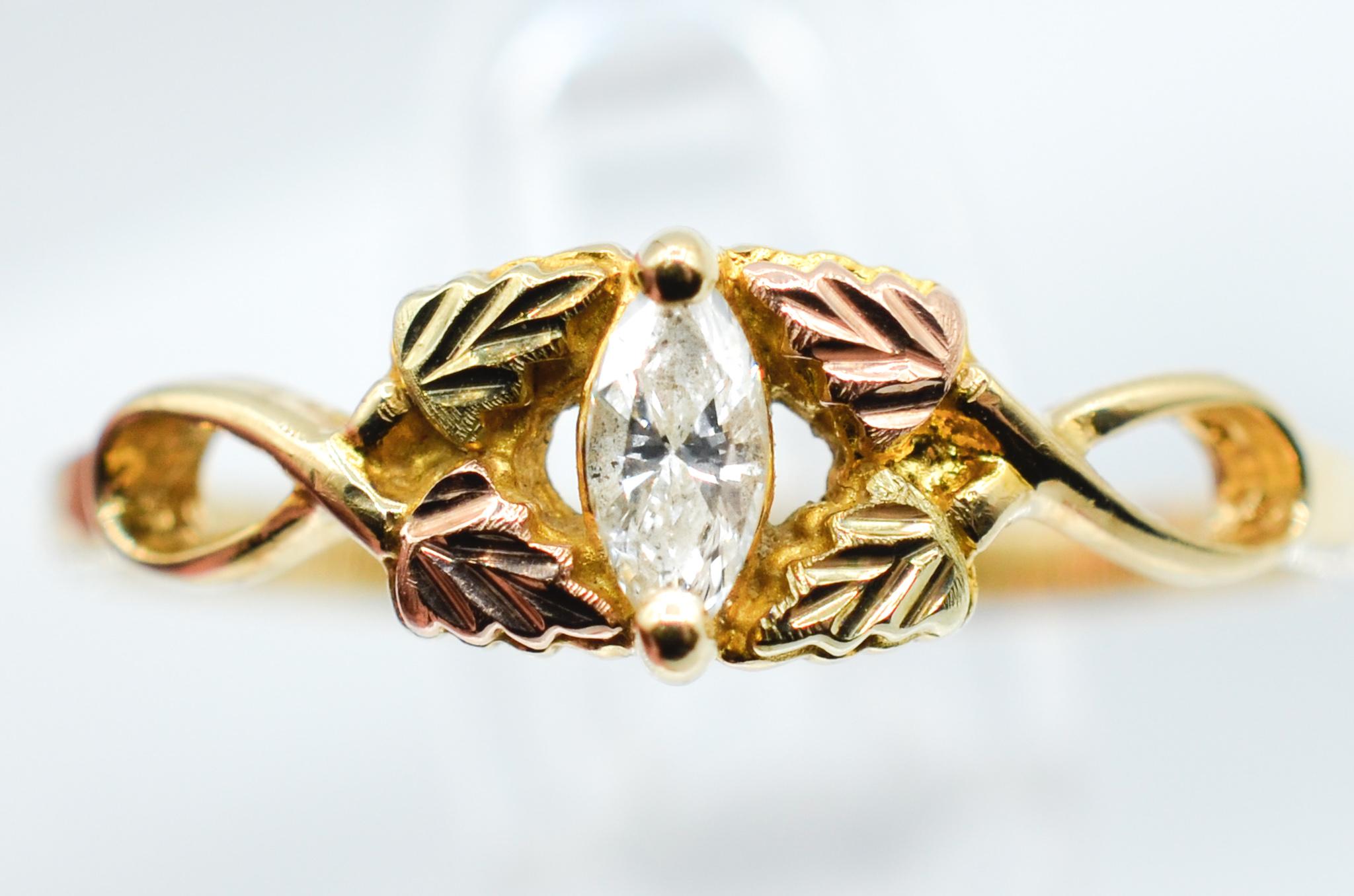 Überraschen Sie die Person, die Sie lieben, mit diesem einzigartigen Black Hills Gold Diamantring für Damen. Es hat petite Hand graviert, Hand platziert, satiniert 12K Rotgold & Grüngold Traubenblätter streichelt ein 1/8ct Marquise Cut Diamond.  