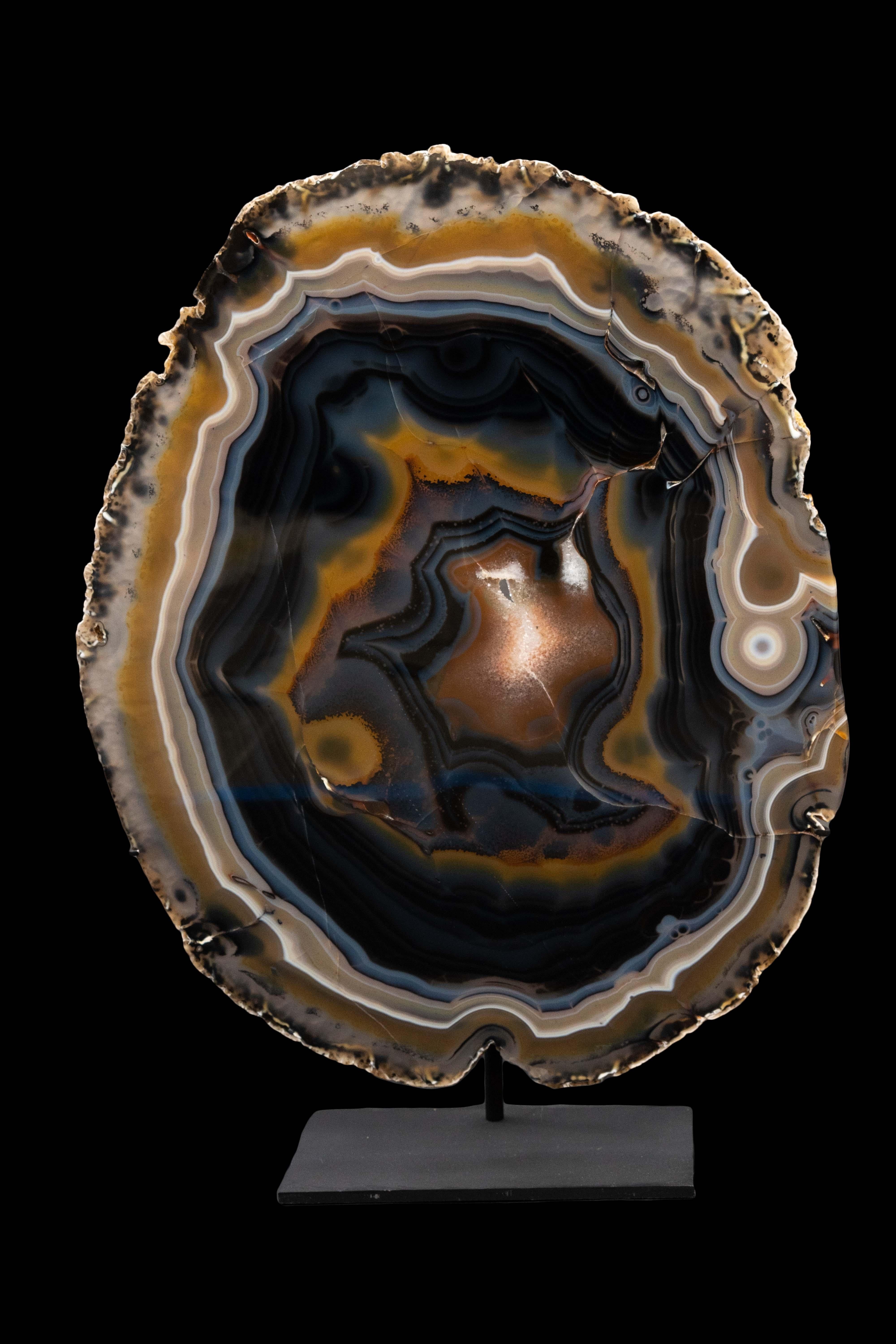 Very large agate slice on a custom mount featuring shades of banded taupe, brown, black, grey and crystalline white. Agate is thought to bring about an emotional, physical and intellectual balance:

Agate minerals have the tendency to form on or
