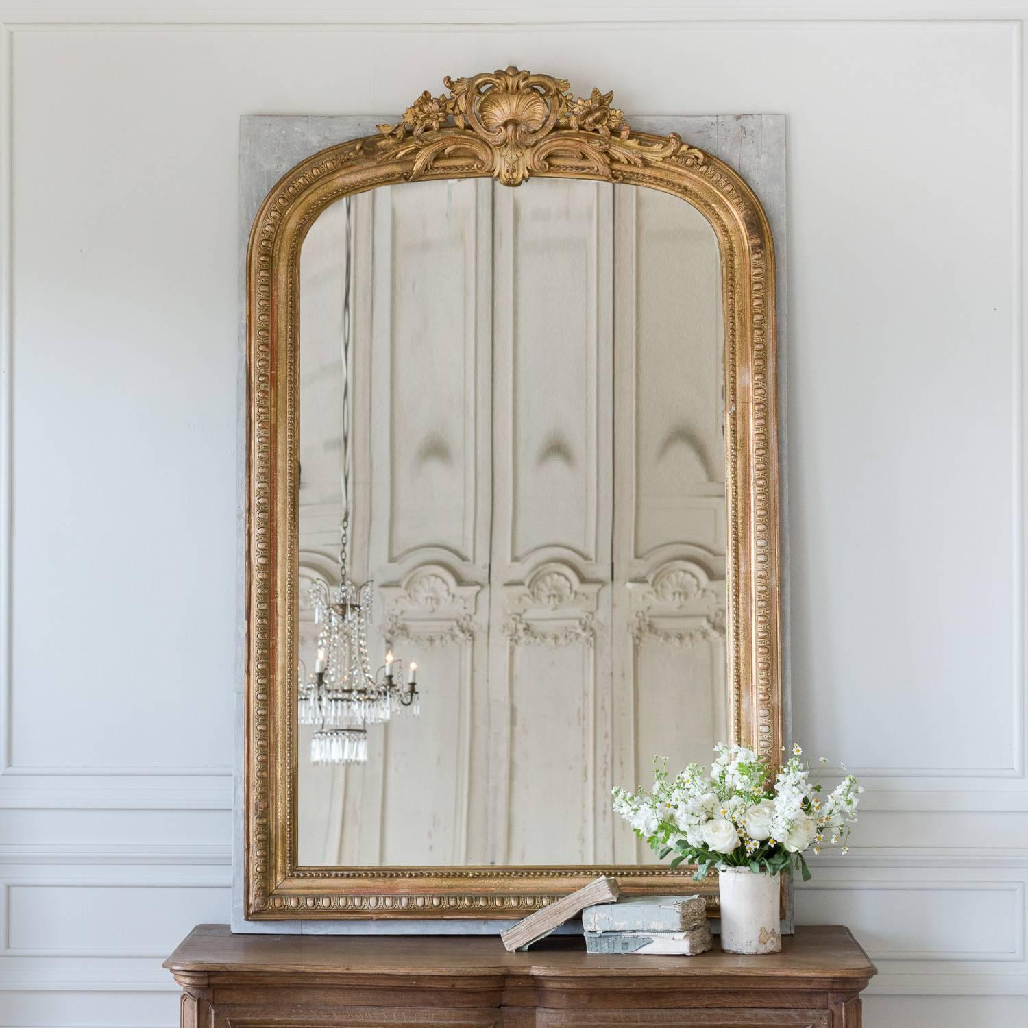 Beautiful, crested mirror with a large shell-themed crest. This unique piece is secured to a soft grey, wood board for extra support. The carved crest scrolls down the shoulders of the frame and dips just slightly over the glass. This wonderful