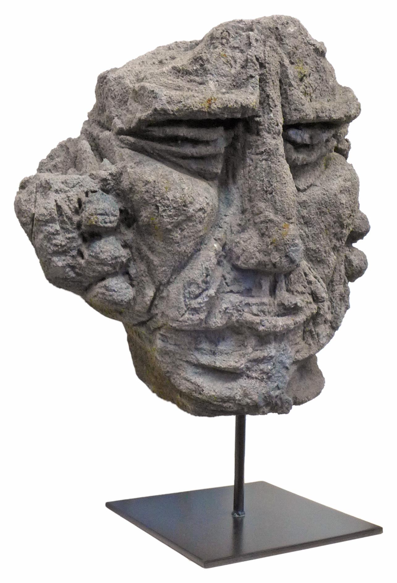 An incredible, mounted, carved lava stone face sculpture. Origin unknown, though likely Polynesian, a wonderful, primitively carved piece with deep, exaggerated features. Seemingly part of a larger work, possibly a bas relief. Set on a contemporary,