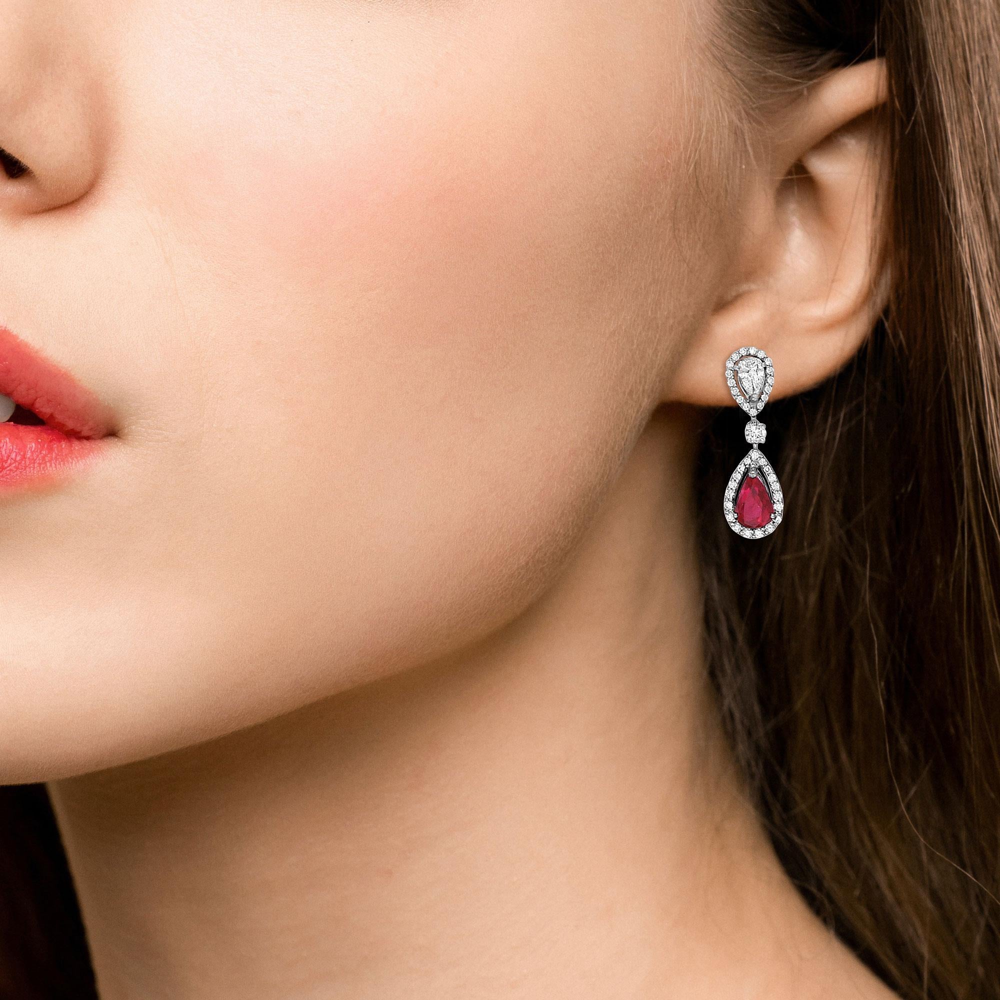 A stunning pair of diamond and ruby pear-shaped drop earrings set in platinum, signed and stamped Moussaieff.

Each earring is set with a singular pear shaped diamond haloed  by smaller round brilliant cut diamonds. Suspended underneath is a drop