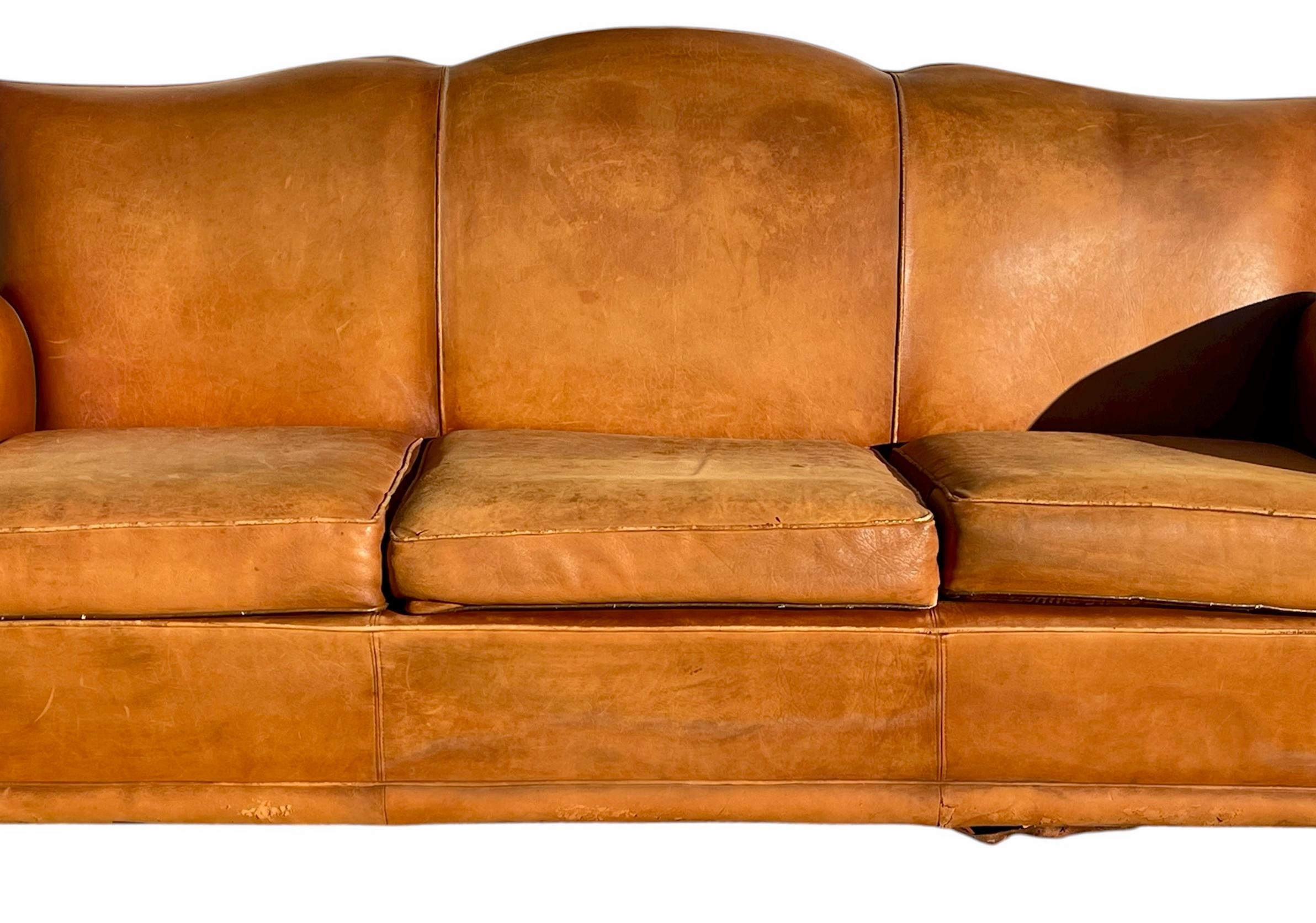 Divano Club a tre posti a forma di baffi, rivestito in pelle color cognac. Le condizioni generali sono buone. Sono presenti alcuni piccoli segni di usura (vedi foto). Circa 1925/1930.
 
 Dimensioni
 Altezza totale 86 cm
Altezza della seduta 39