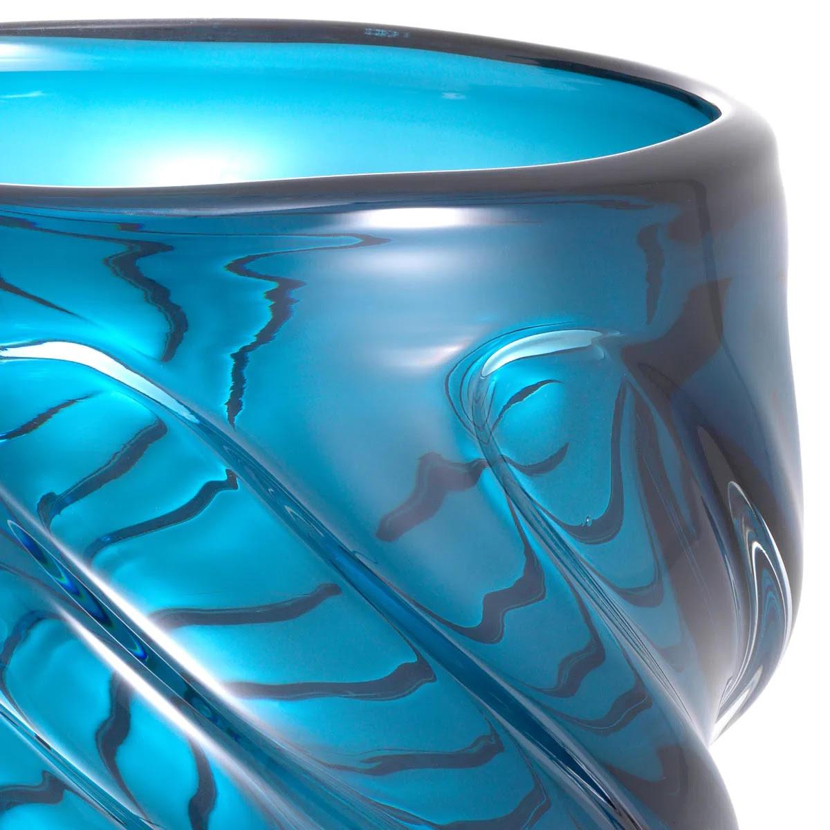 Mouth-blown blue glass vase.

Prettily shaped to display beautiful floral arrangements, this small vase is a functional and elegant addition to your home decor.

Handcrafted from blue glass, it features an elegant swirl pattern.

Ø 24  H. 25 cm