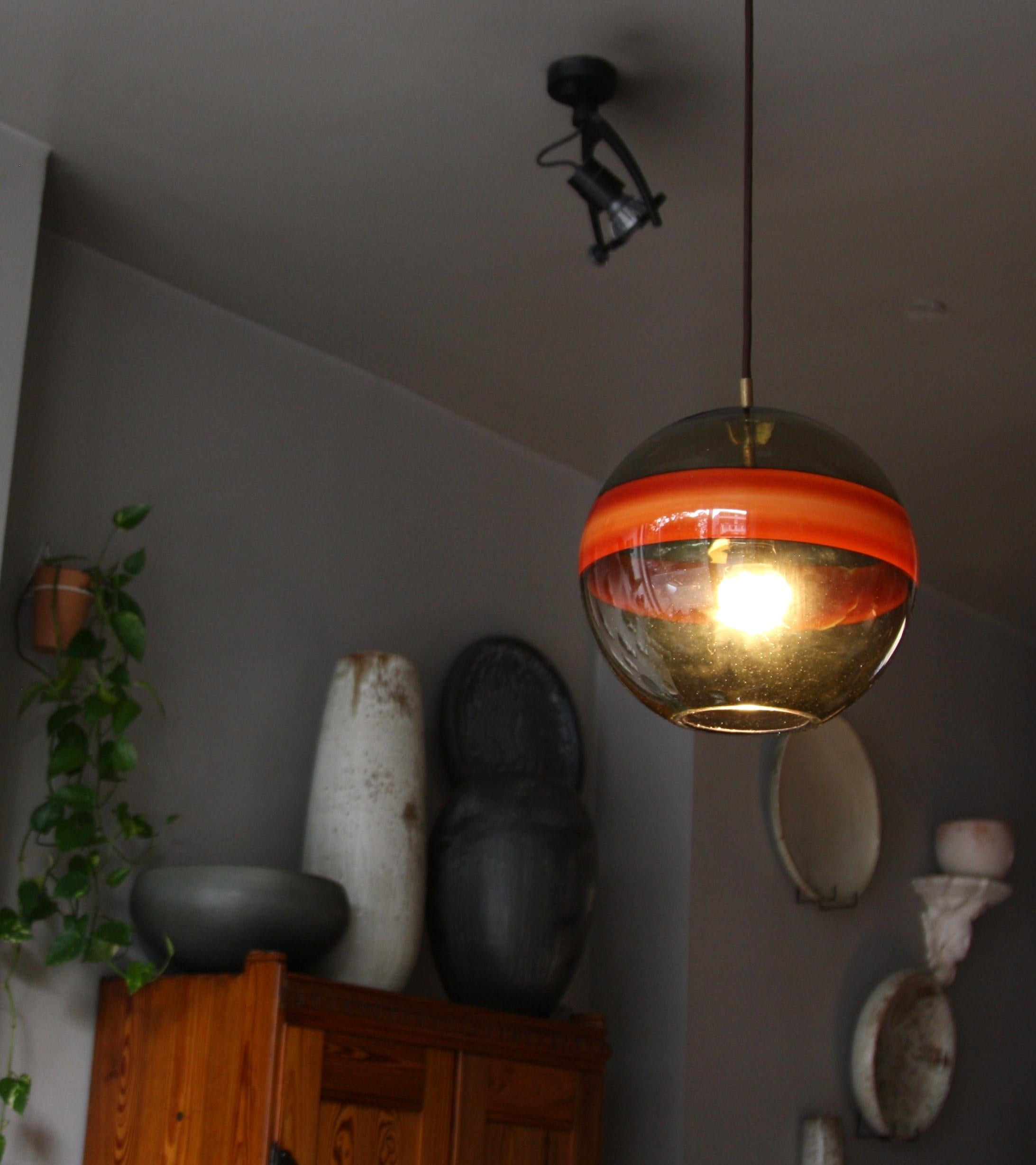 A vintage mouth-blown glass pendant light designed and made in Italy, attributed to Venini, circa 1955.
The predominant color of the glass globe is translucent ‘smoke’ (brown/green/grey) a popular choice of color for glass makers in the mid-20th