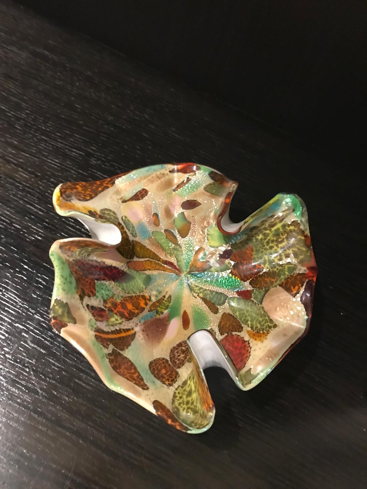 Il s'agit d'une pièce unique en verre d'art de Murano avec une forme et un motif asymétriques dans des teintes automnales d'or, de vert, de rouille et d'orange, le tout accentué par des feuilles d'or soufflées dans le verre.

Ce plat étonnant