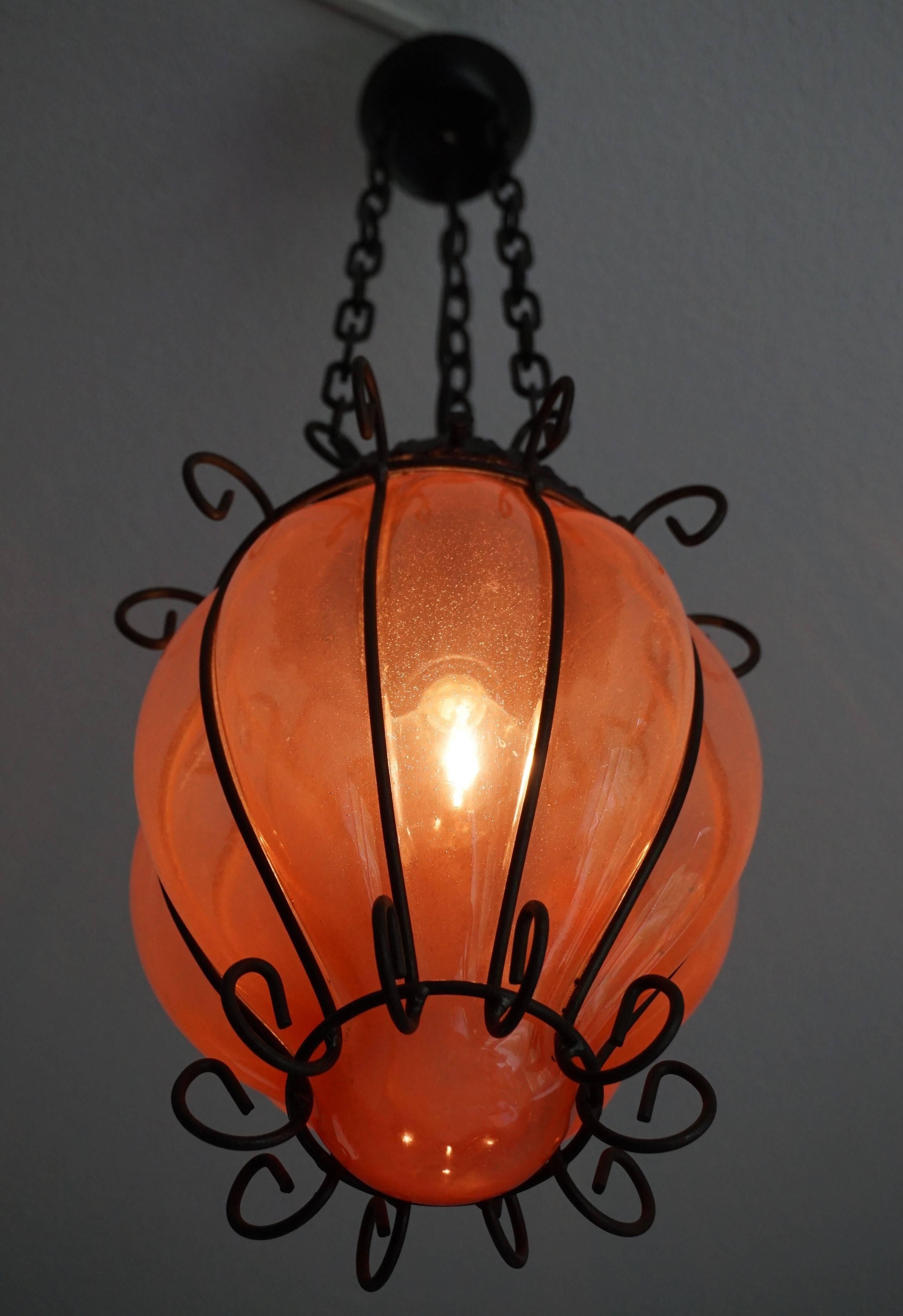 Beautifully mouthblown, reddish glass in metal frame, from circa 1950.

This timeless single light pendant is beautiful in shape and the mouth blown, red glass is a rare sight to see. This one of a kind lamp could create the perfect atmosphere in a