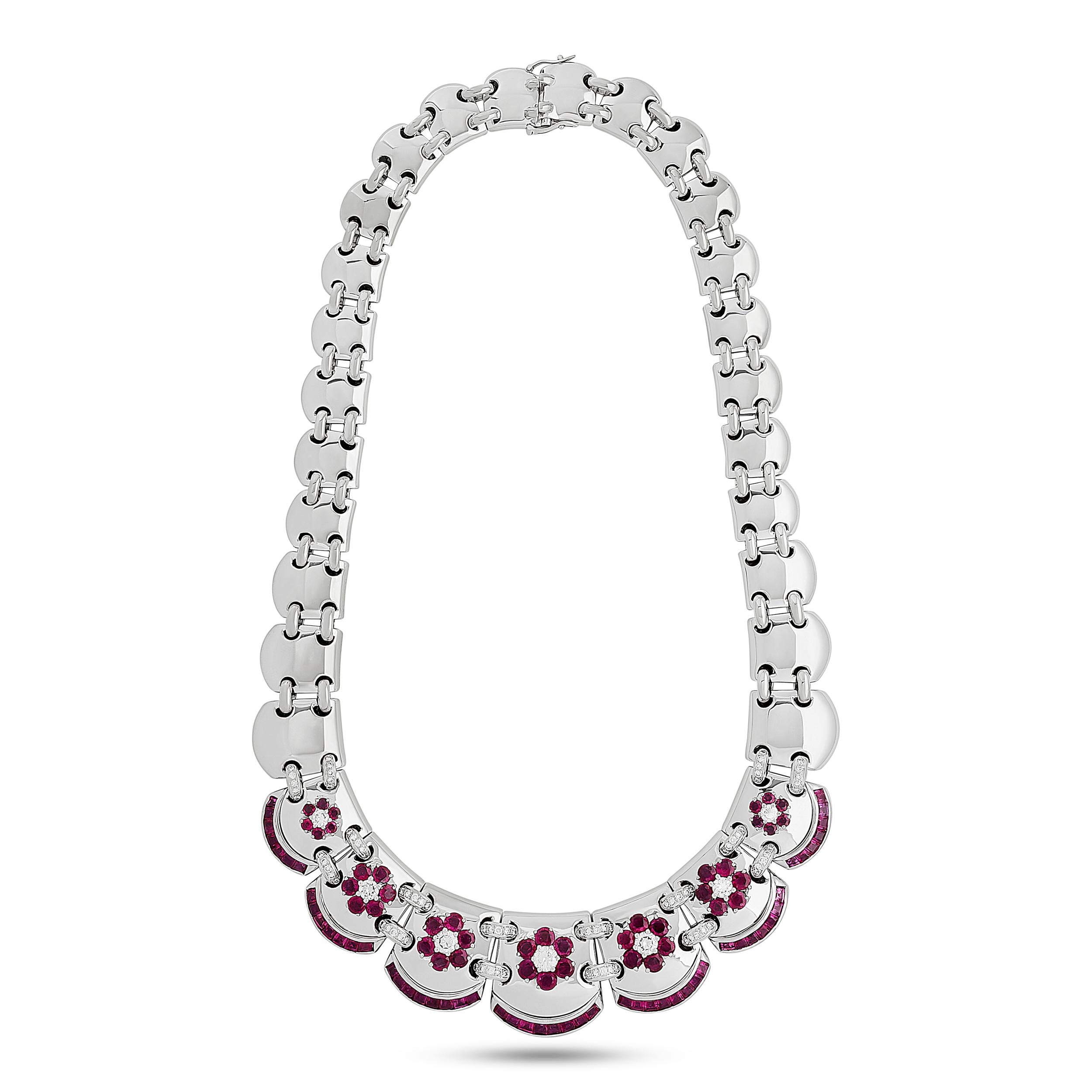 Encased in a luxurious wooden box, this Mouawad suite features a breathtaking ensemble of 18 karat white gold jewelry, comprising a necklace, earrings, bracelet, and ring, each piece meticulously crafted with vibrant rubies and dazzling diamonds,